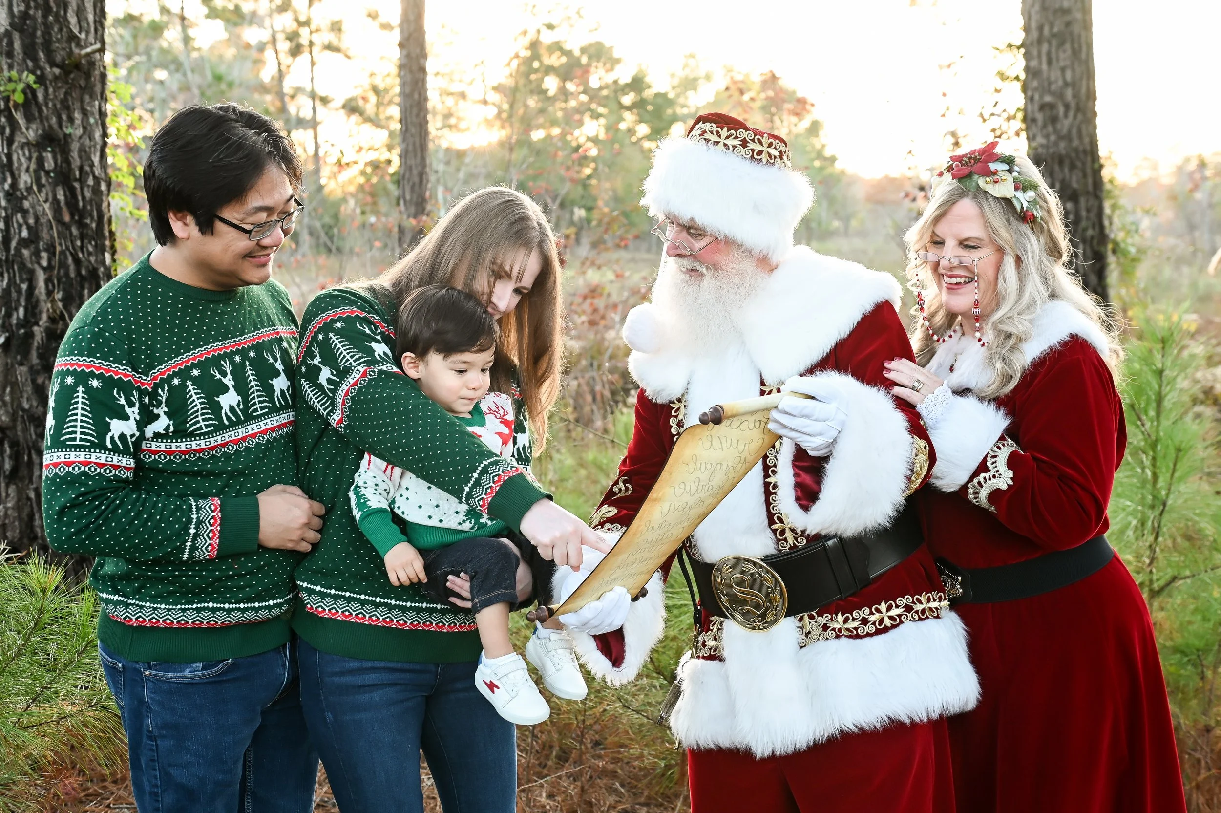Santa and Mrs Claus showing baby nice list