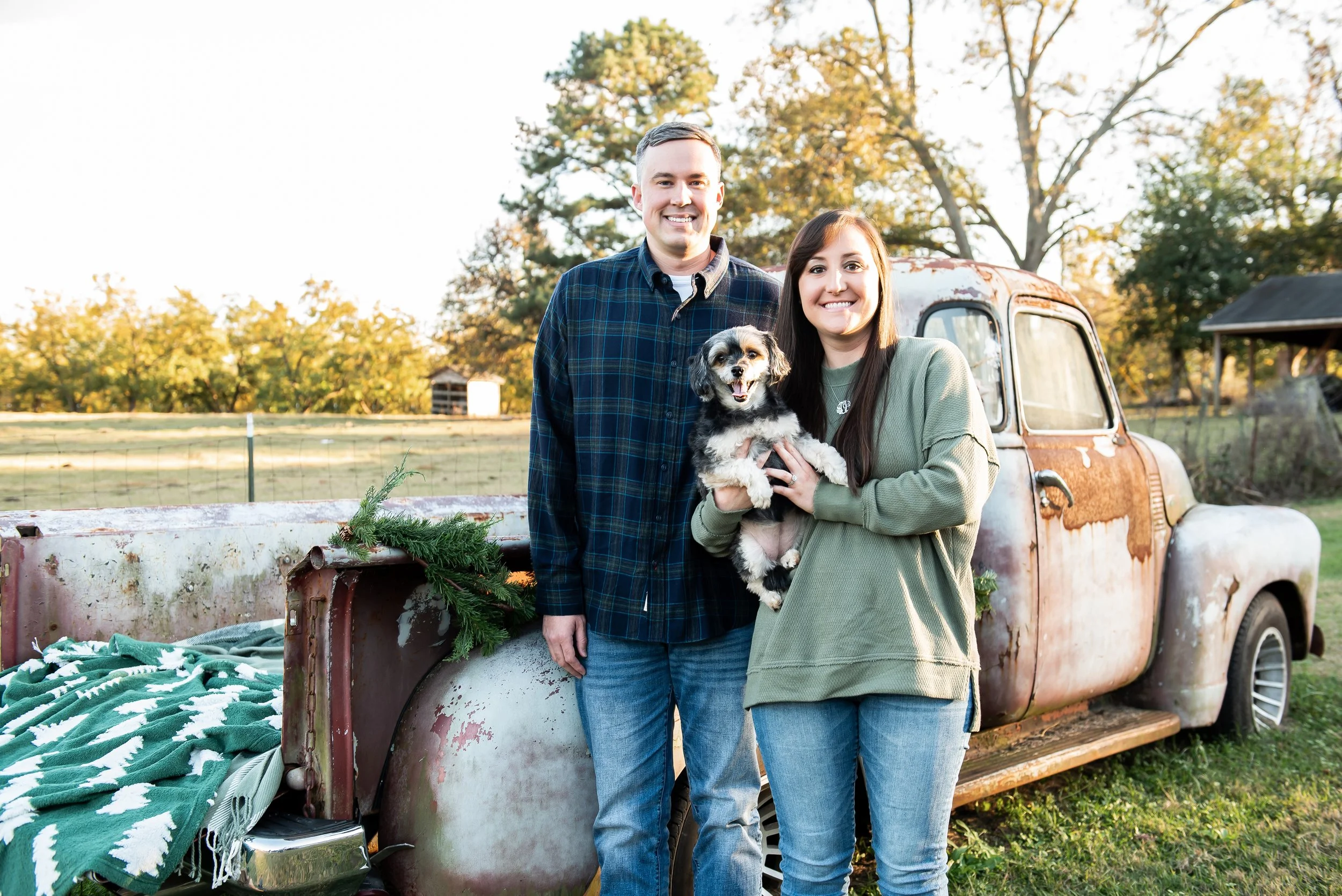 Couple with dog standing by old truck