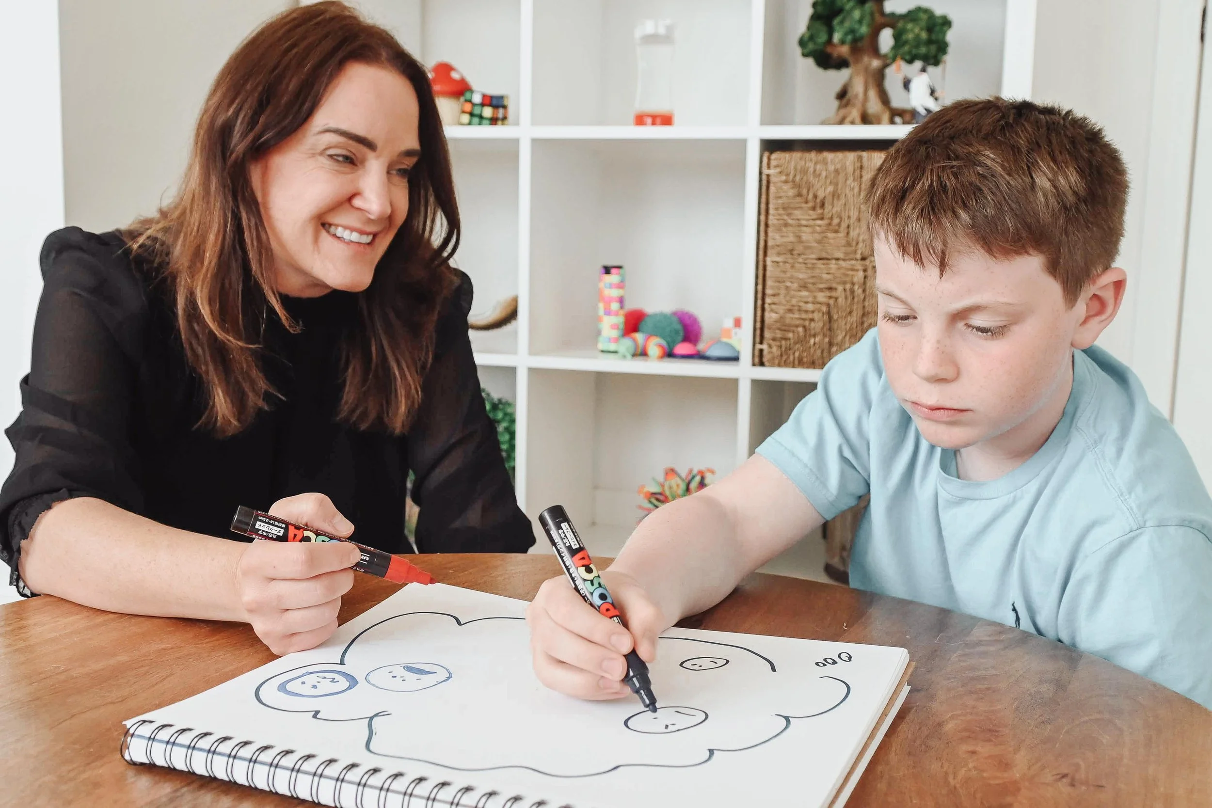 Child psychologist and boy drawing together during ADHD therapy in Calgary at Creative Sky Psychology, building focus, confidence, and connection.