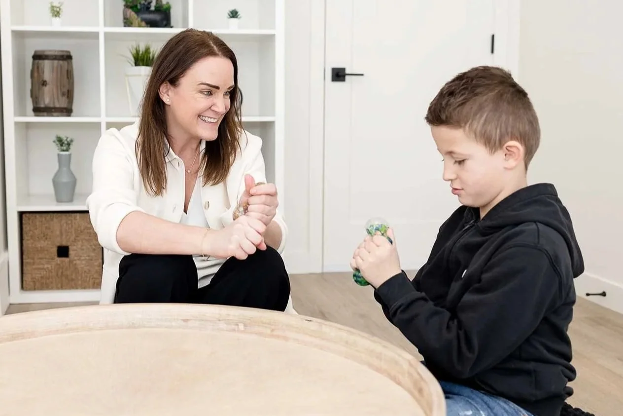 A child psychologist sitting and connecting warmly with a young child during a session at Creative Sky Psychology in Calgary.
