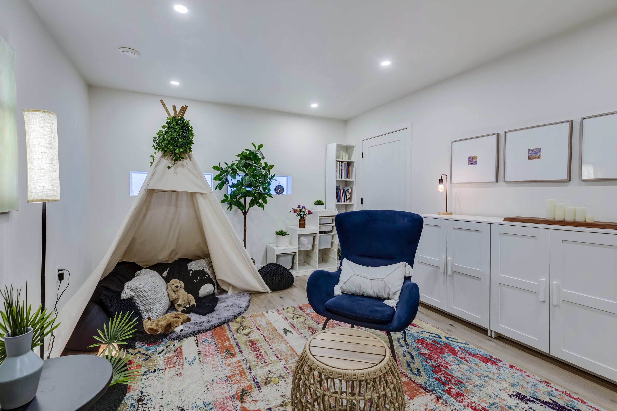 A calm, cozy child therapy room at Creative Sky Psychology in Calgary, with a play teepee, soft seating, plants, and a warm patterned rug.
