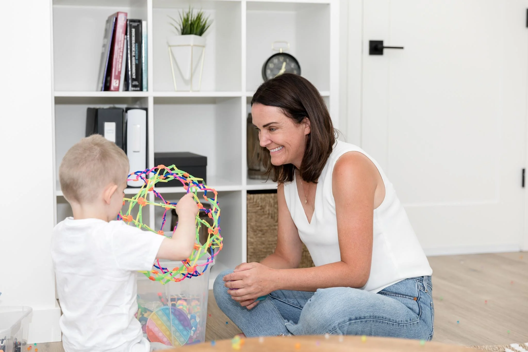 Child psychologist smiling with a young boy as he plays during a therapy session at Creative Sky Psychology in Calgary