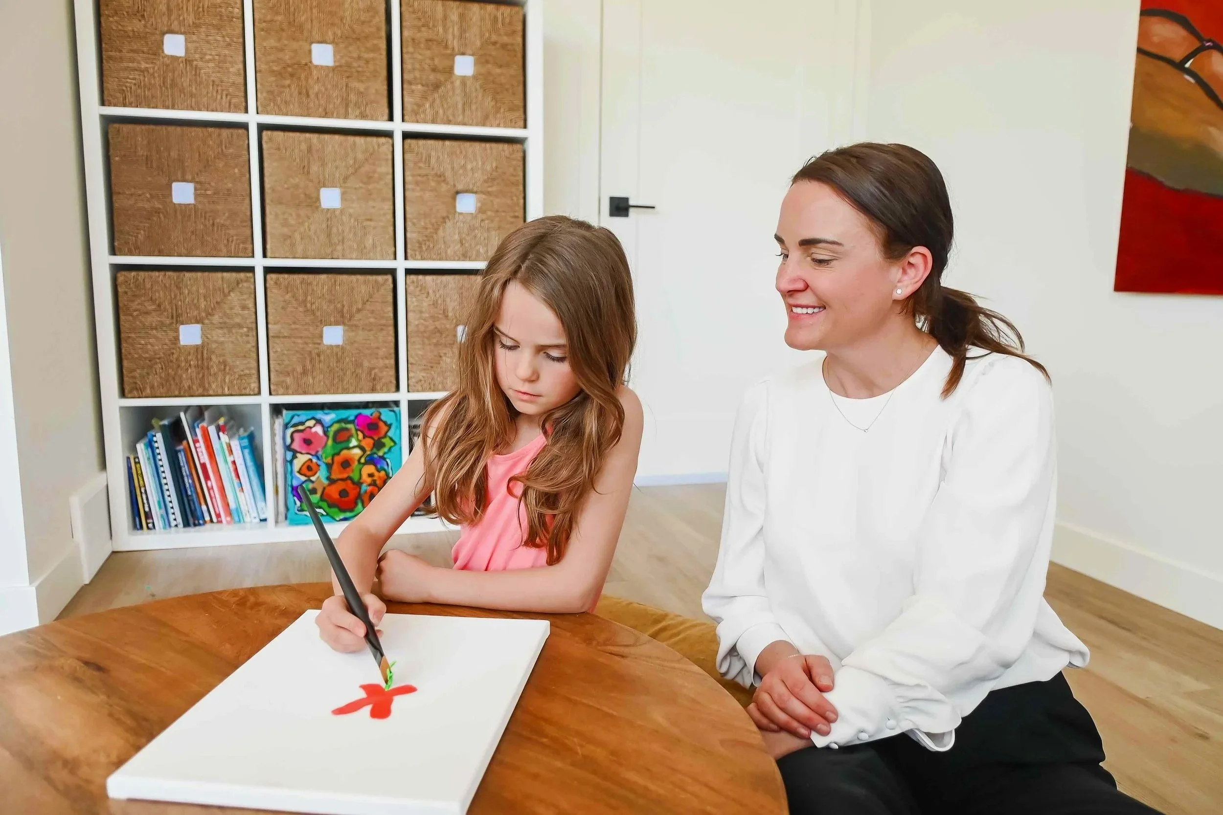 Child psychologist in Calgary sitting with a young girl as she draws during a therapy session at Creative Sky Psychology