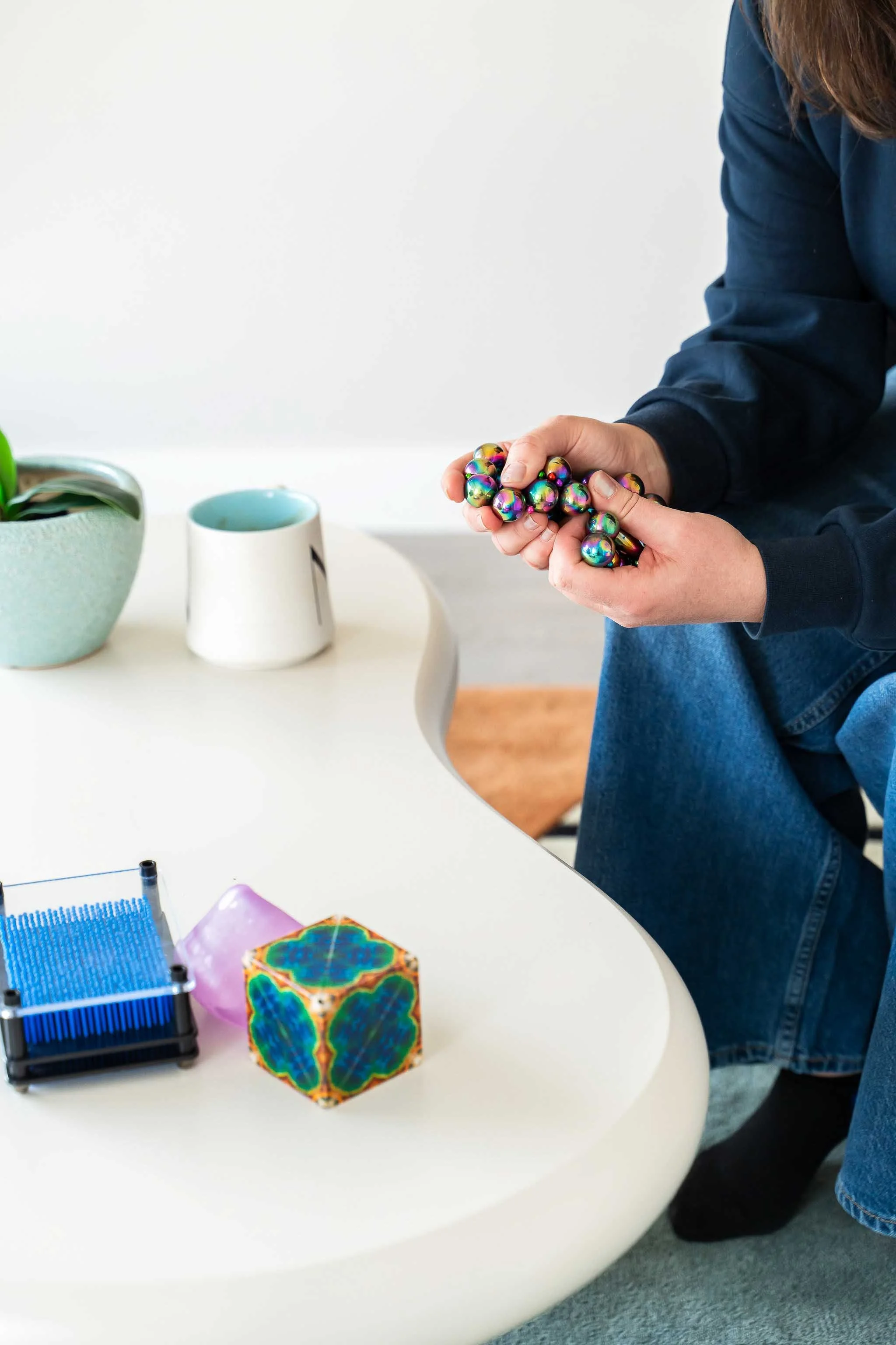A teen holding a colourful sensory fidget during a therapy session at Creative Sky Psychology in Calgary, with a calm cup of tea nearby.
