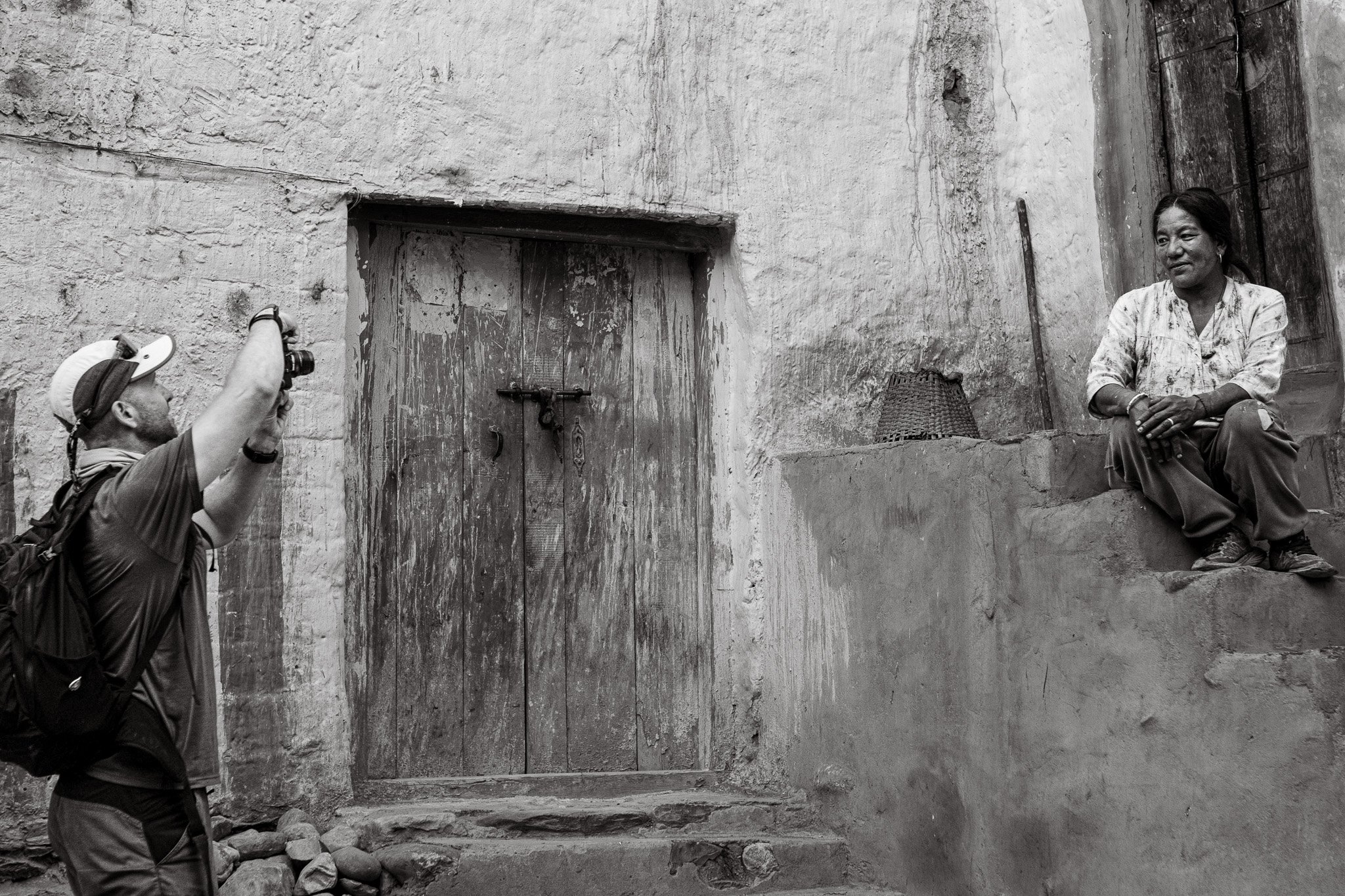 Black and white photograph of a man photographing a local woman in Upper Mustang, Nepal.
