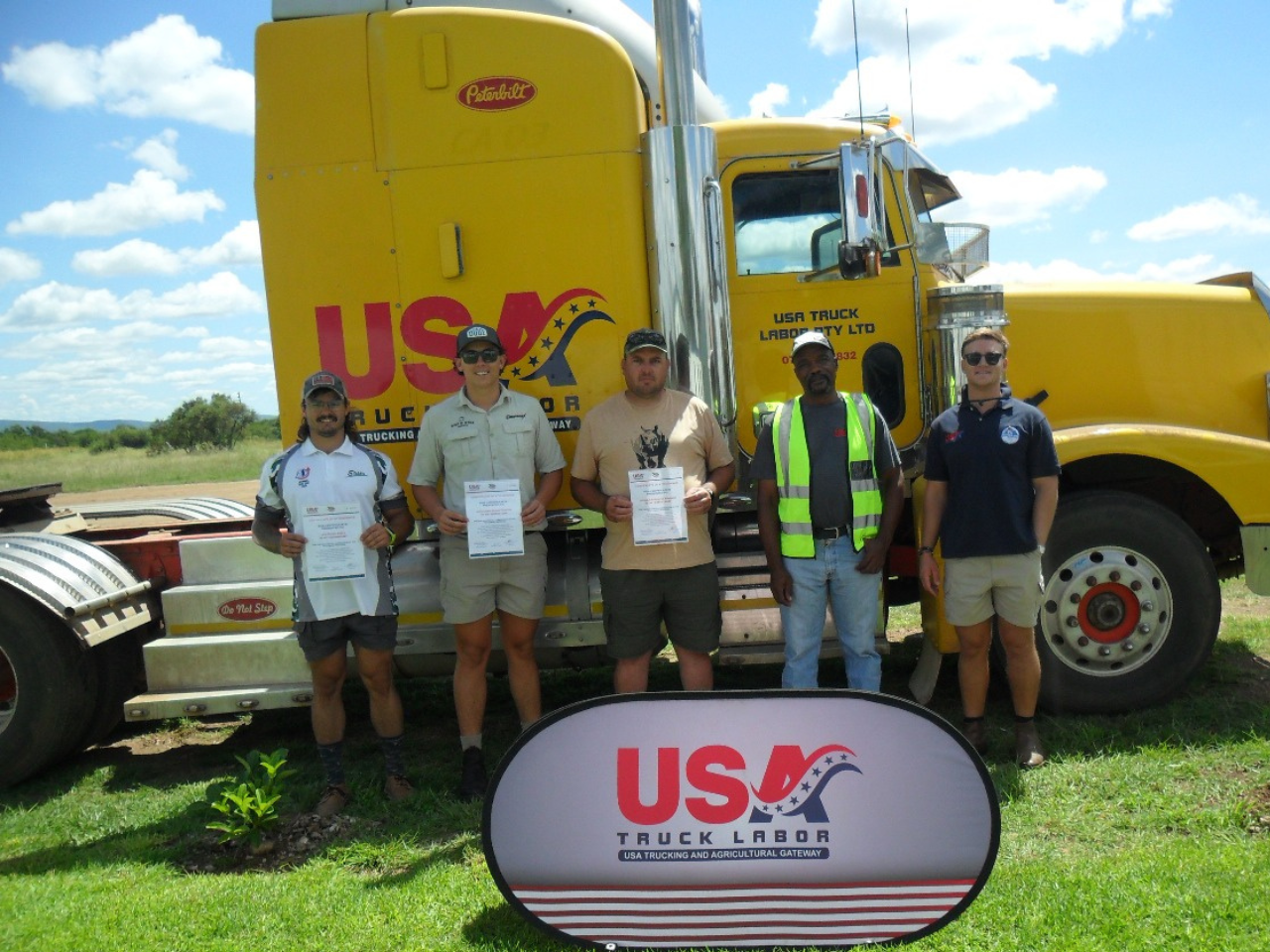 group of seasonal farm jobs training grads standing in front of yellow truck