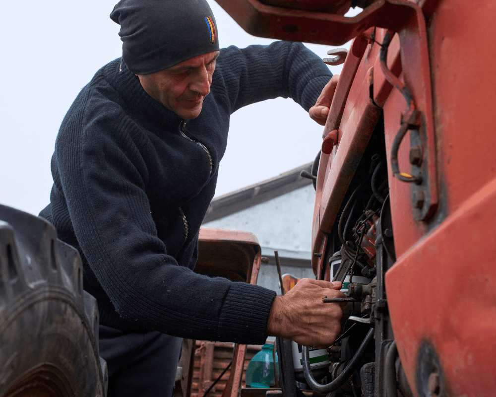 image of a worker on an H2A job fixing a tractor