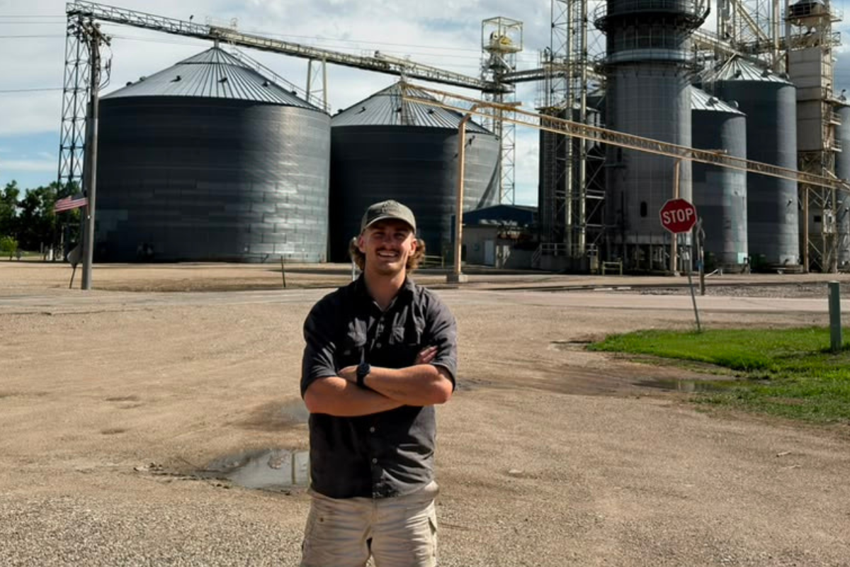 picture of a farmworker in front of grain elevators