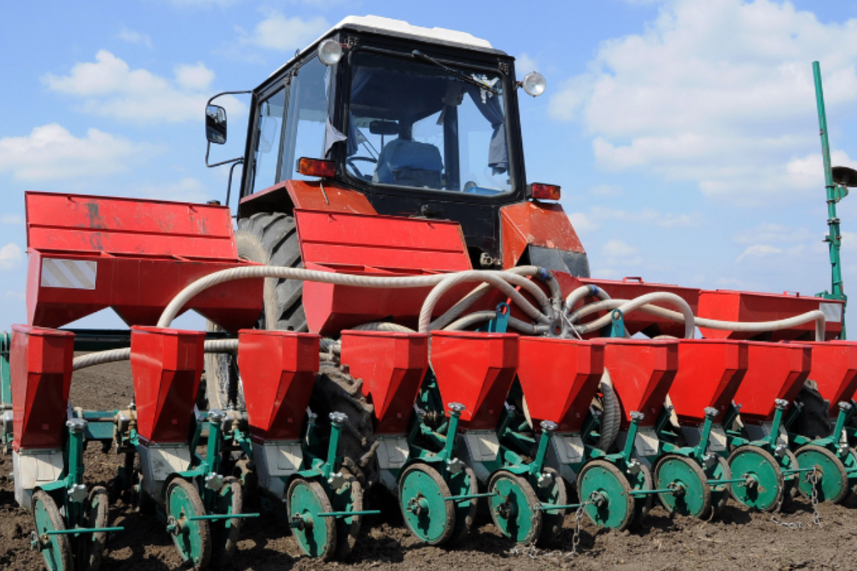red farm tractor with seeder attachment