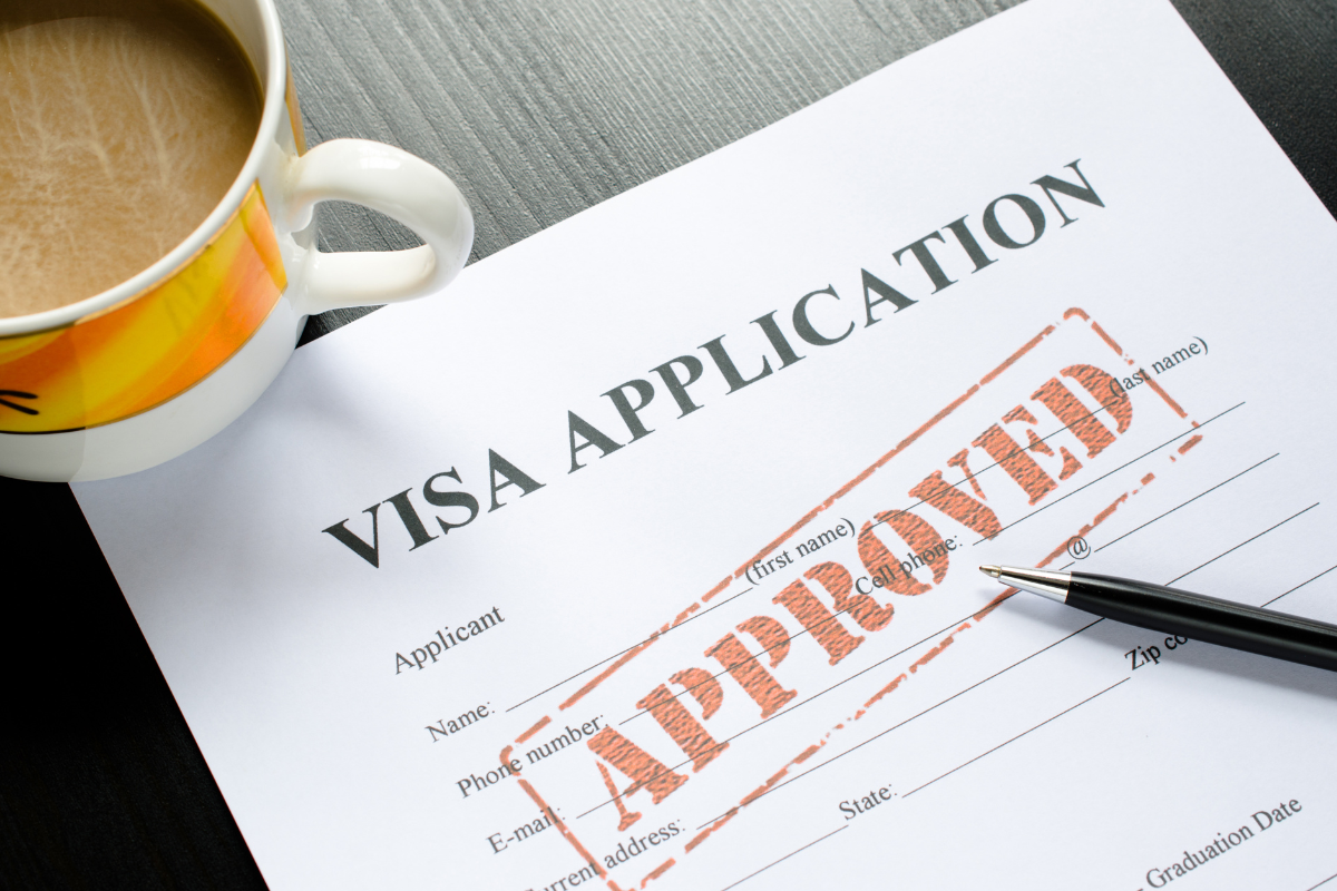 image of a H2A or H2B visa application document with approval stamp sitting next to a cup of coffee