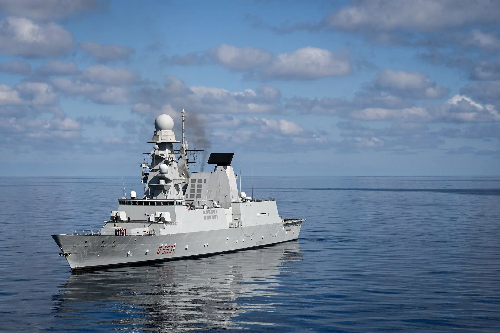 Italian Navy warship on calm sea under blue sky with clouds