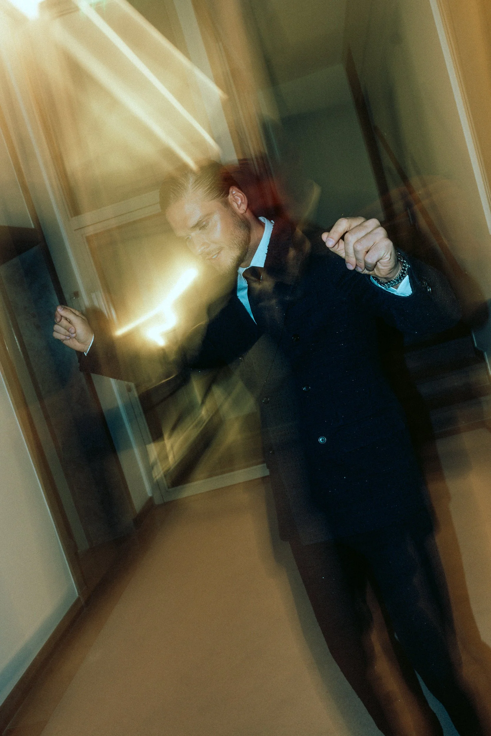 Ein Mann (Rurik Gislason) in dunklem Anzug tanzt in einem Raum mit vernebelter Bewegung und Lichtreflexen.