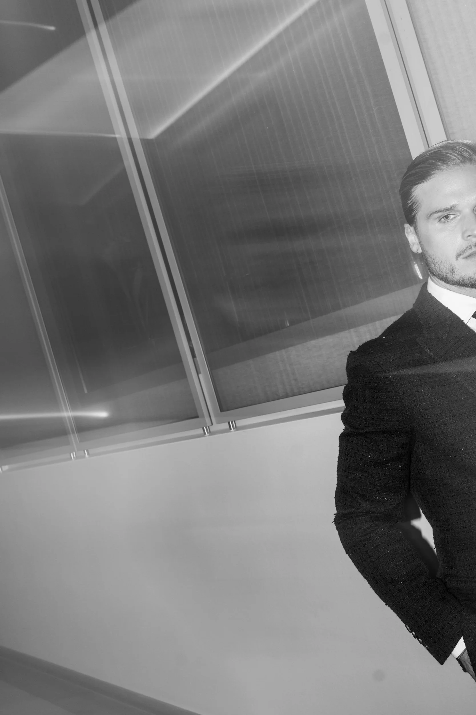 Foto eines Mannes (Rurik Gislason) in formeller Kleidung mit stehendem Haar, nur die rechte Seite seines Gesichts ist sichtbar, vor einer modernen Wand mit reflektierenden Paneelen.