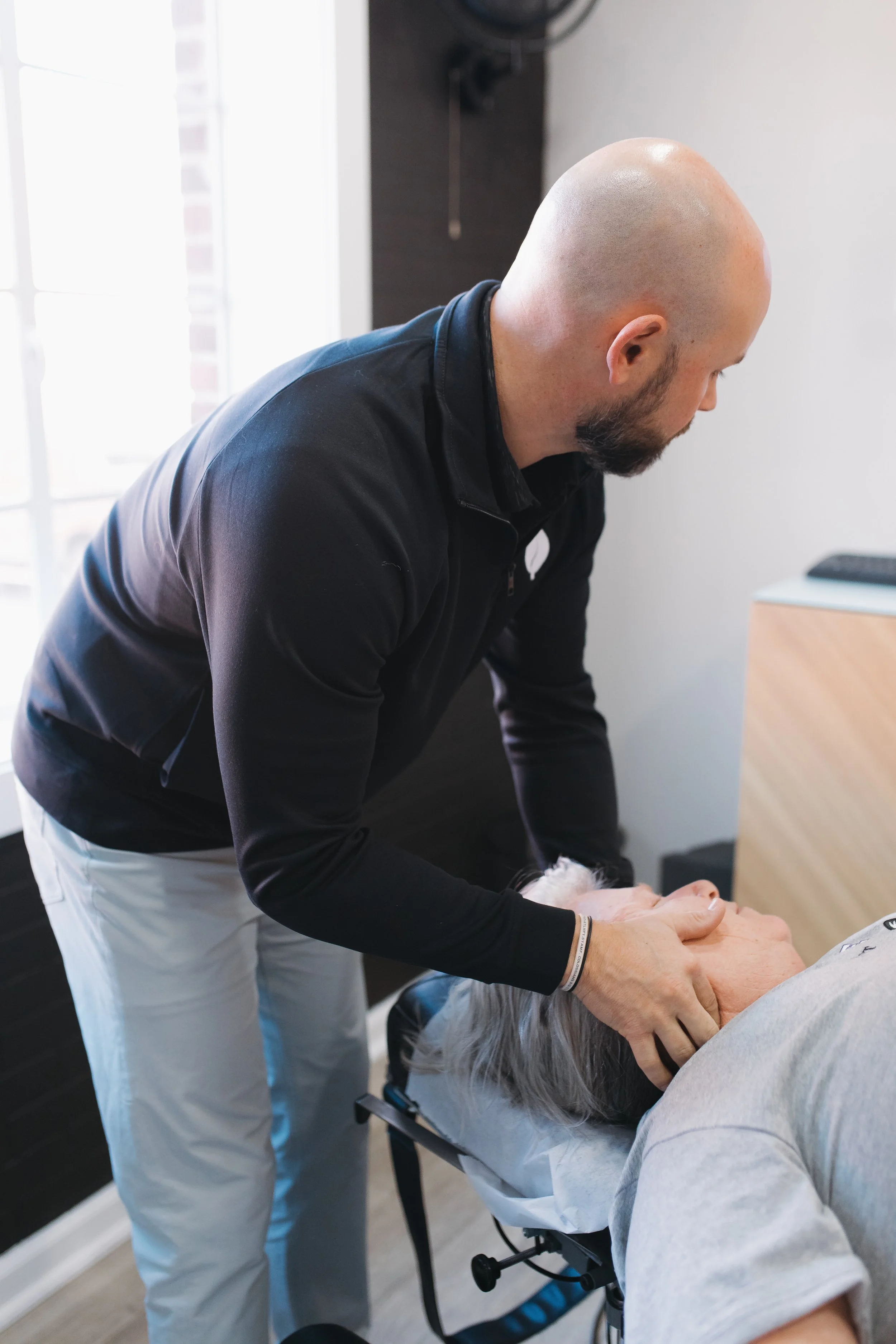 Chiropractor adjusting an elderly patient's neck in a clinic.