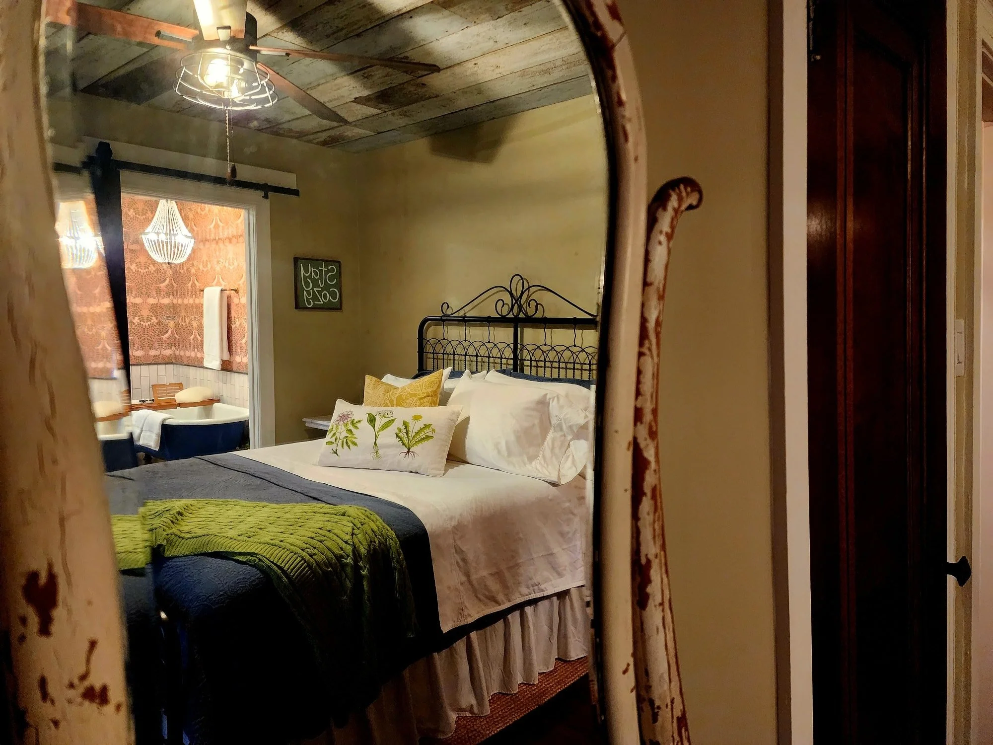 Tucked beneath a weathered barnwood ceiling, this cozy retreat feels like stepping back in time &mdash; with all the comforts of today. The master bedroom features a wrought-iron bed layered in crisp linens, botanical pillows, and a soft knit throw t