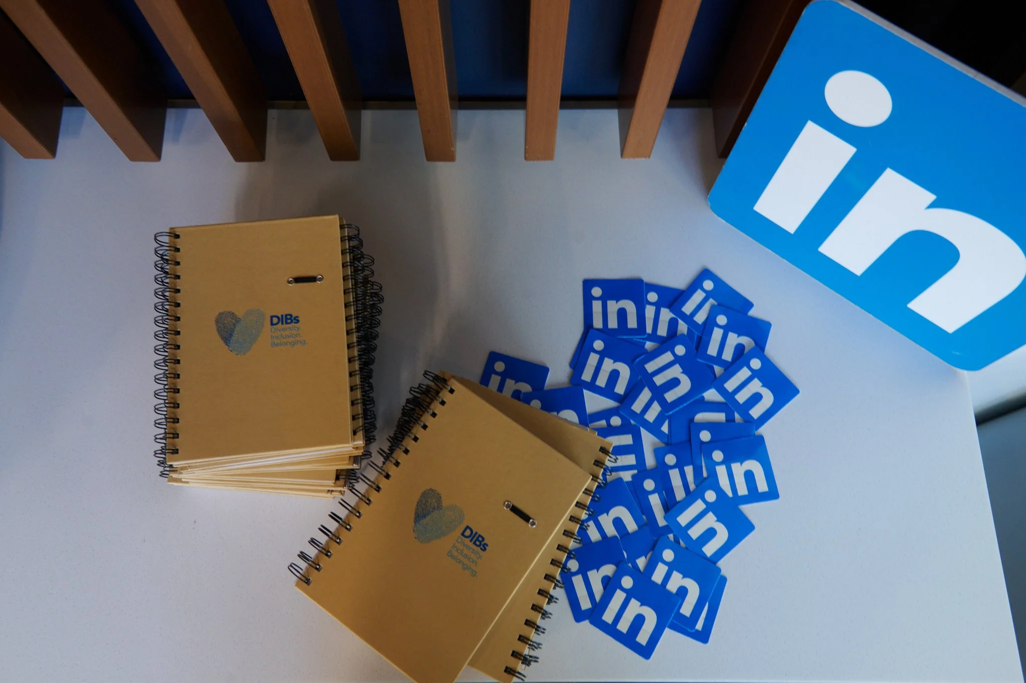 A stack of notebooks with "Dilla" branded on the covers, next to a set of LinkedIn branded stickers and sign that has the LinkedIn logo.