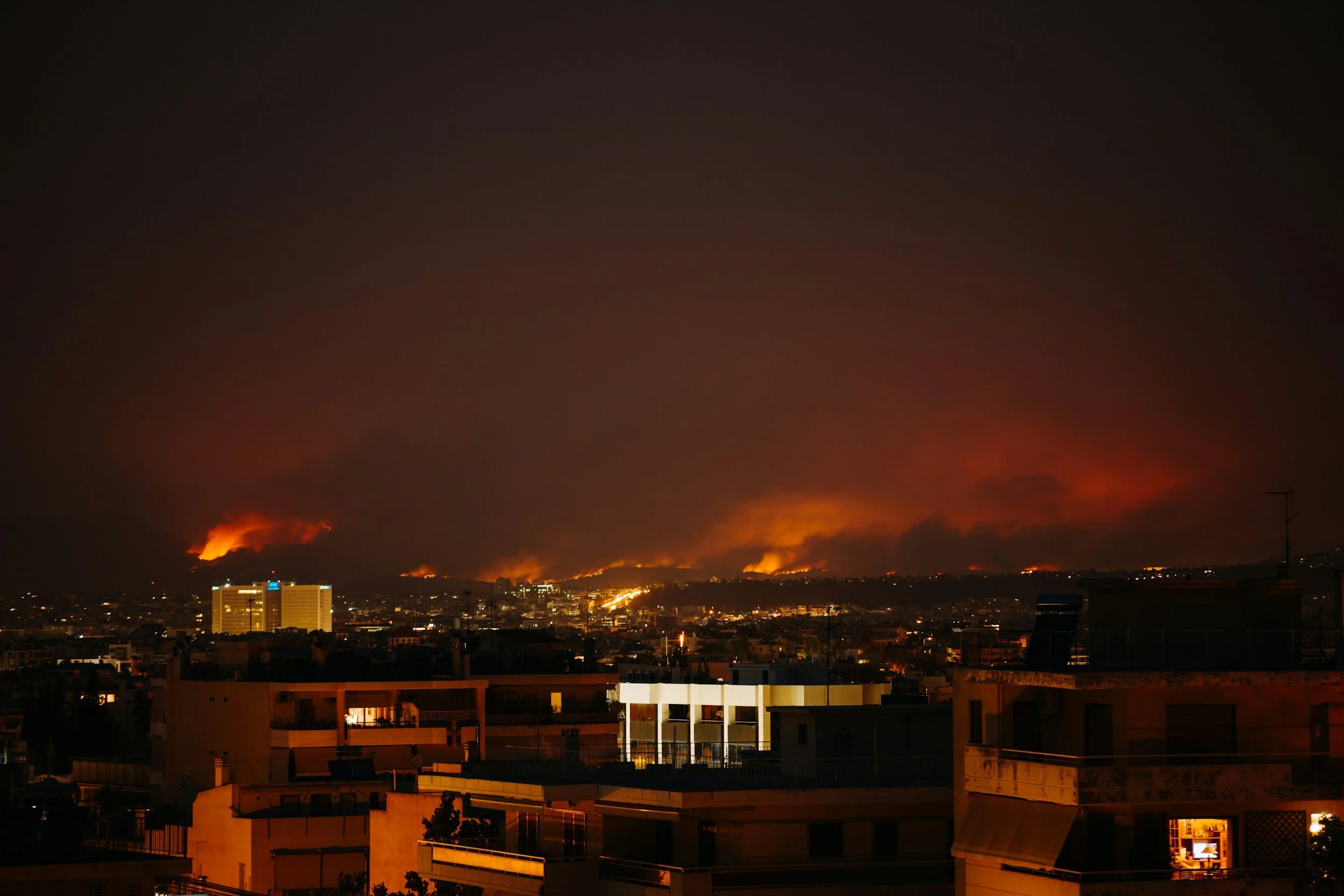 Photograph of buildings in an urban environment with an active wildfire in the background