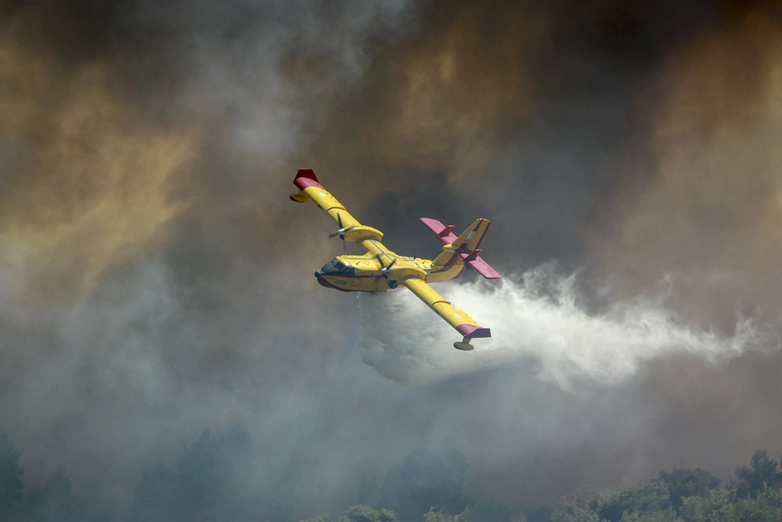 Photograph showing an aerial firefighting aircraft dropping water on an active wildfire