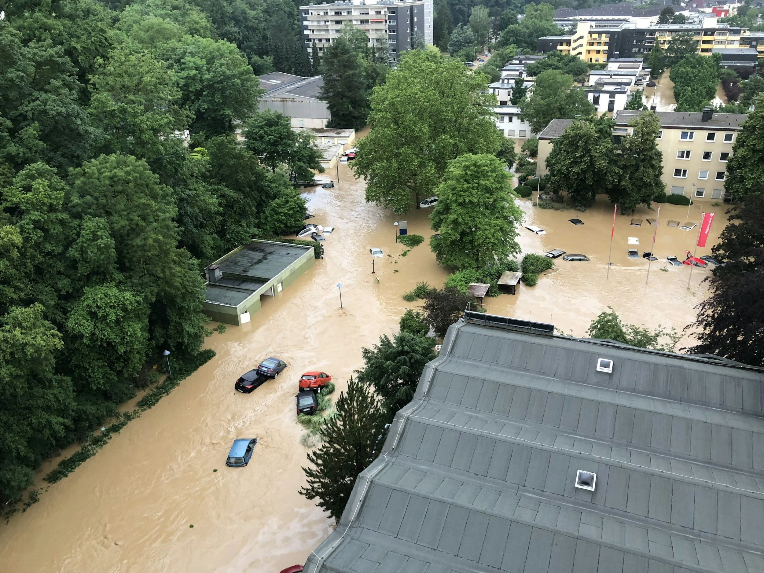Photograph showing a flooded town from above with several cars trapped in standing water