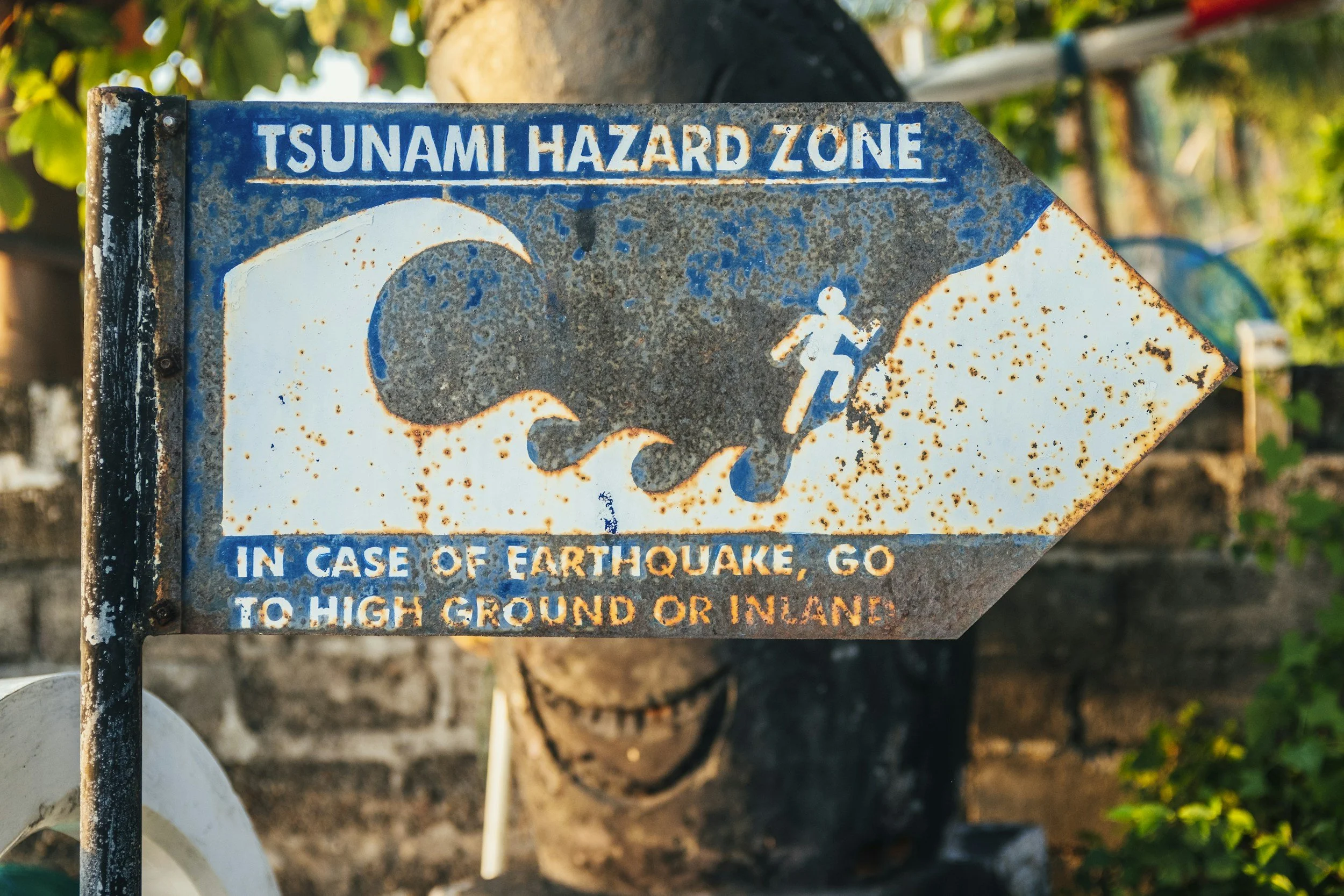 Image of a rusted sign directing people to a Tsunami Hazard Zone