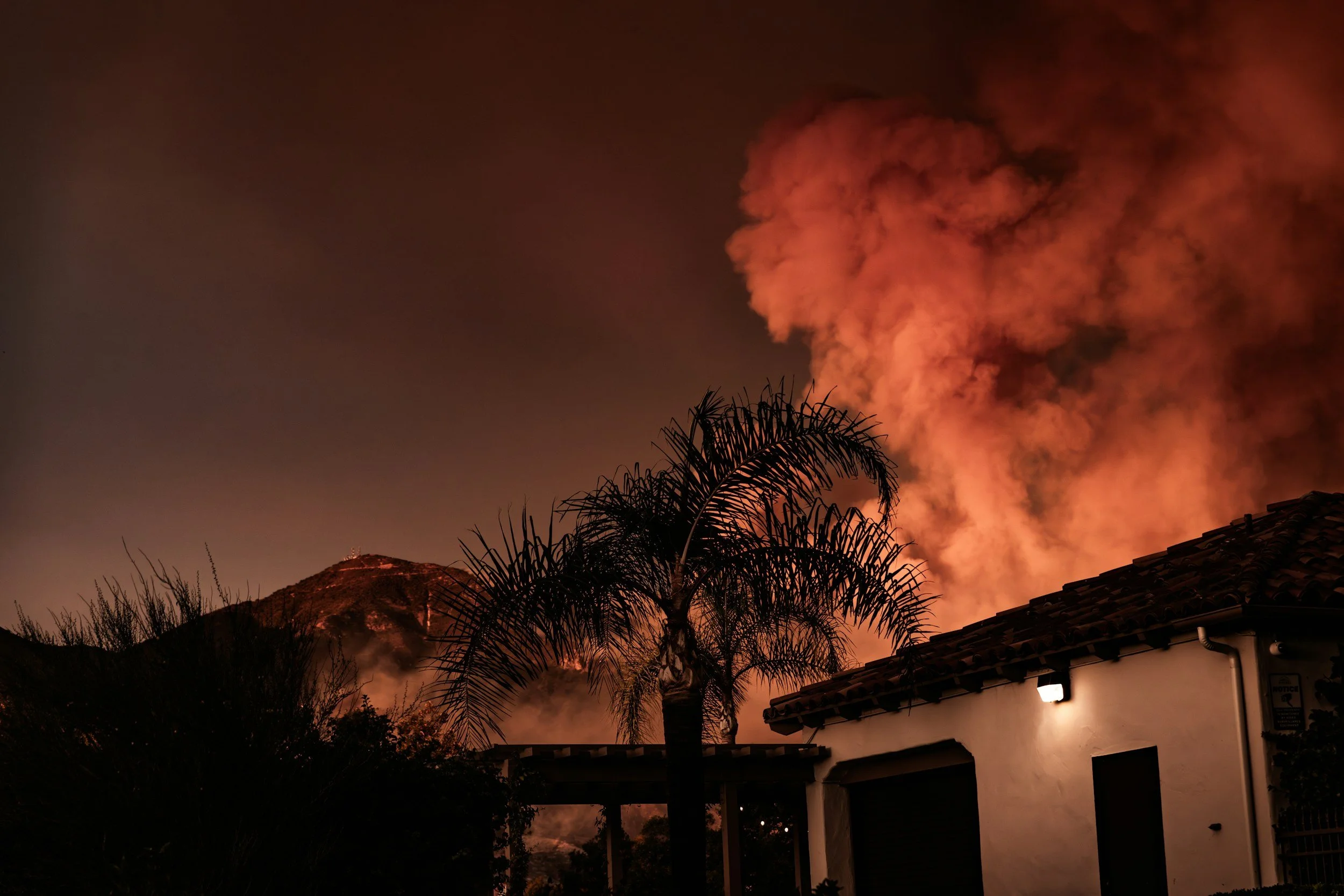 Close up of a home with a wildfire nearby in the background