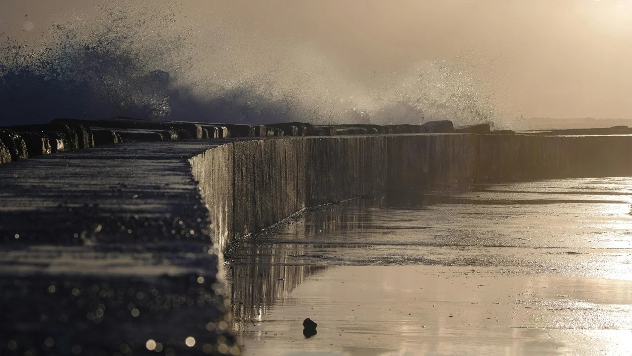 Dramatic picture of waves crashing against a seawall at sunset