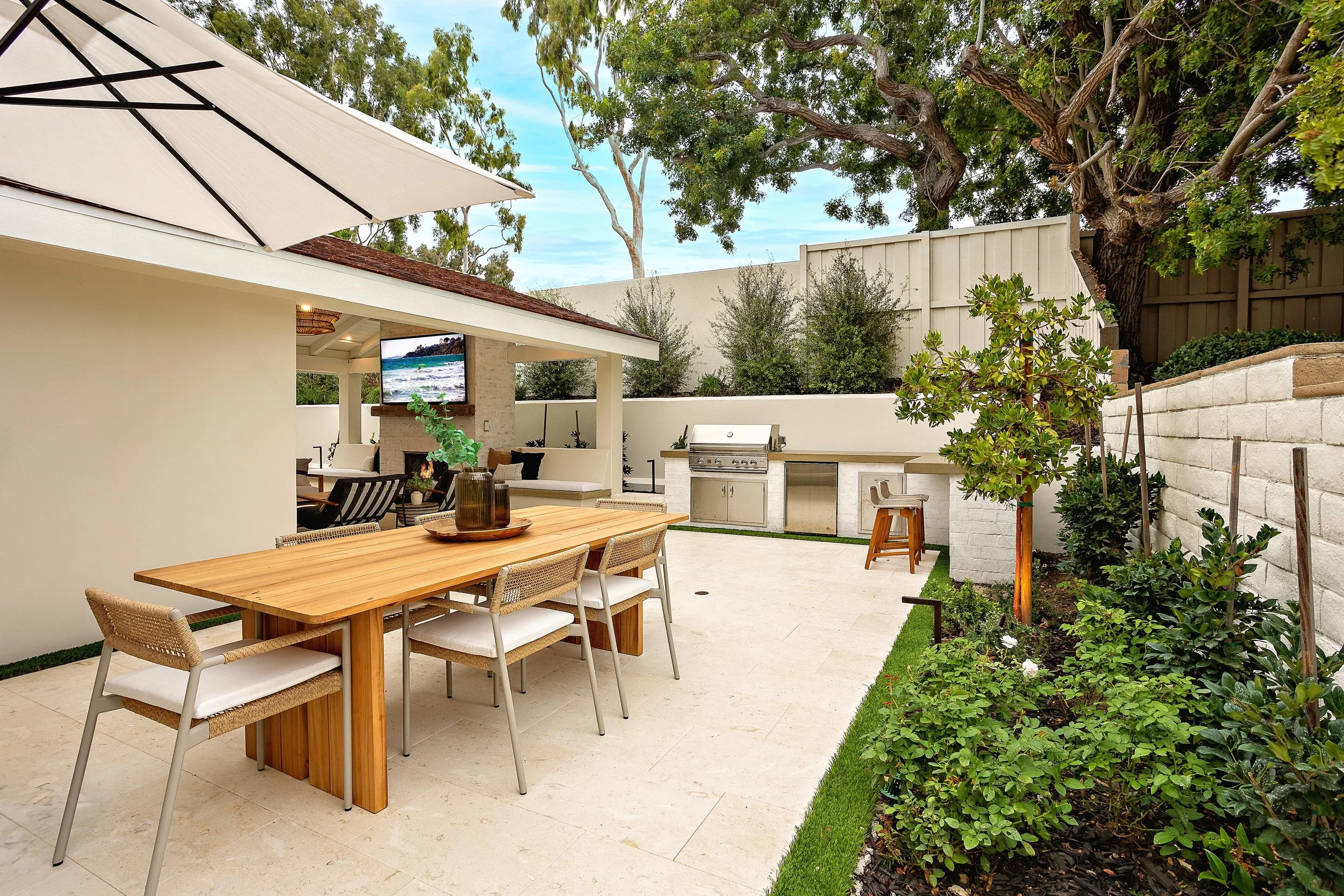 Outdoor dining area and kitchen with modern seating and greenery, designed by VW Design and Build in Newport Beach.