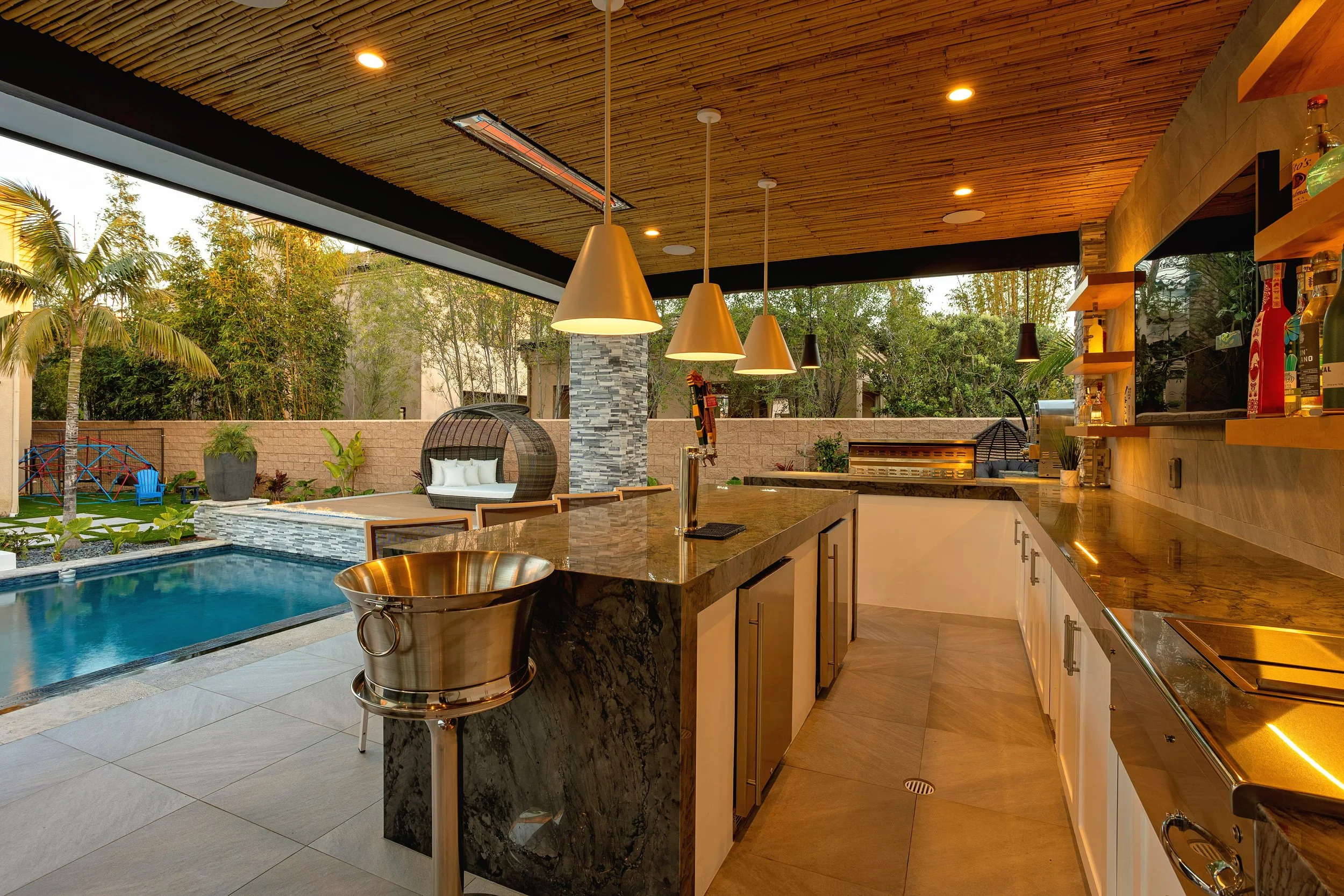 Modern outdoor kitchen with pool and seating area designed by VW Design and Build in Huntington Beach.
