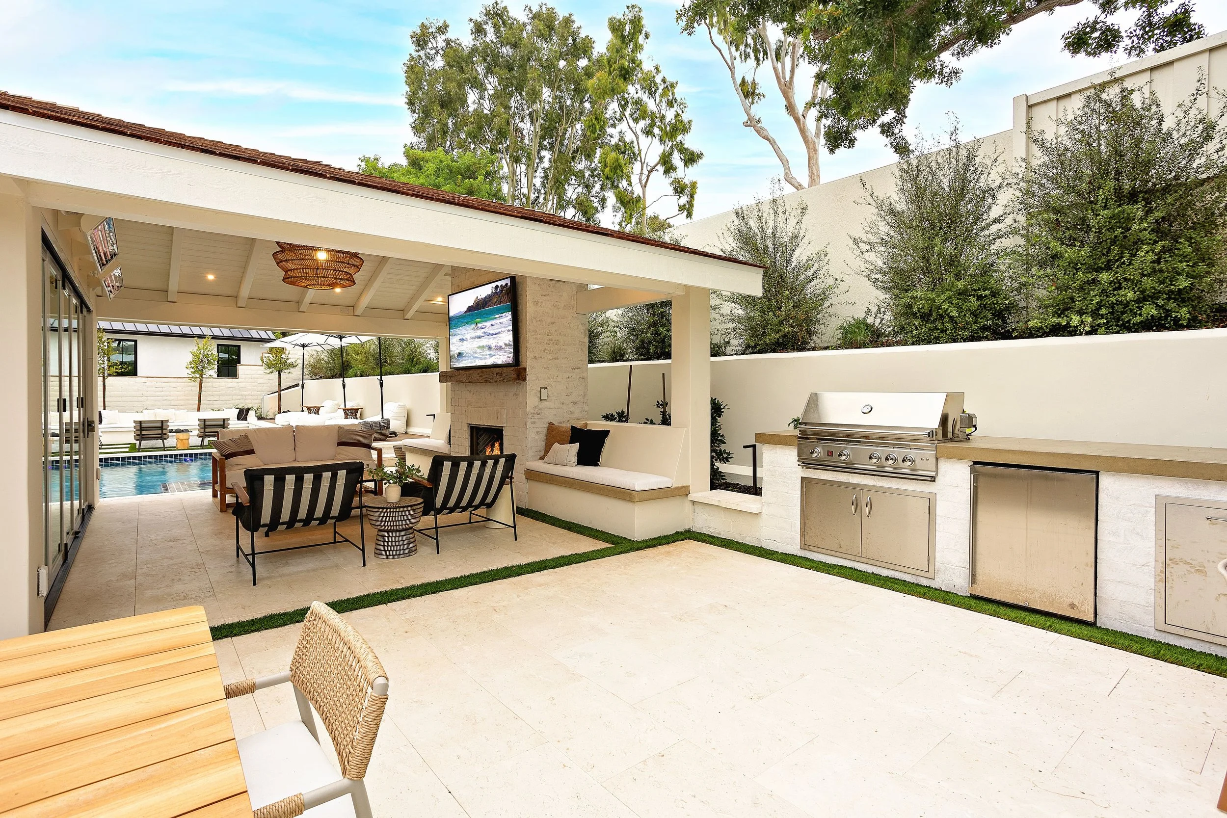 Covered outdoor lounge and kitchen area with modern seating and built-in BBQ, designed by VW Design and Build in Newport Beach.