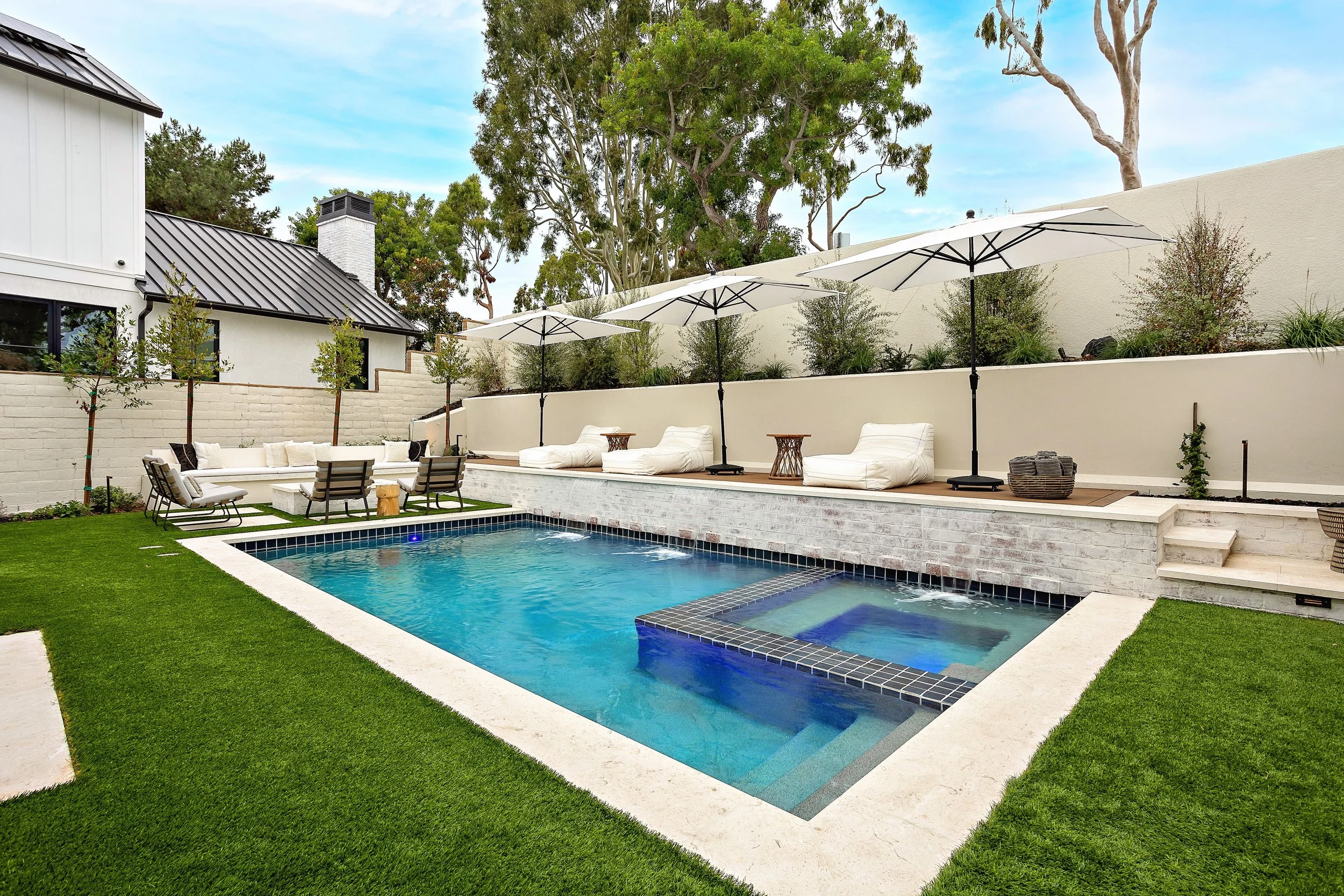 Modern outdoor pool with lounge chairs and built-in seating, designed by VW Design and Build in Newport Beach.