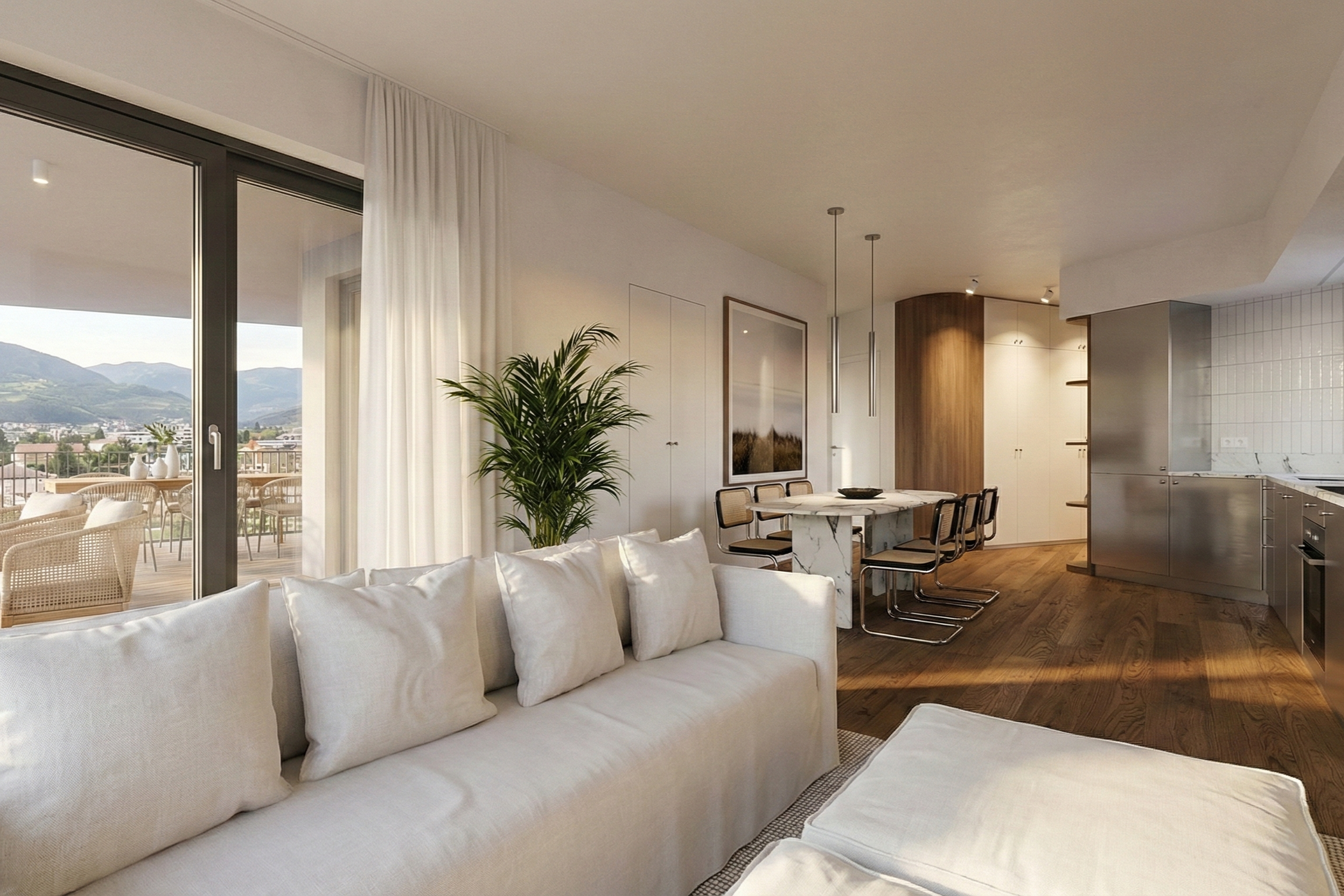 Interno di un soggiorno con divano bianco, large finestra con tende bianche, vista sul balcone con mobili da esterno e montagne sullo sfondo, decorazioni moderne, quadro alle pareti, tavolo da pranzo in marmo con quattro sedie, cucina con ante in met