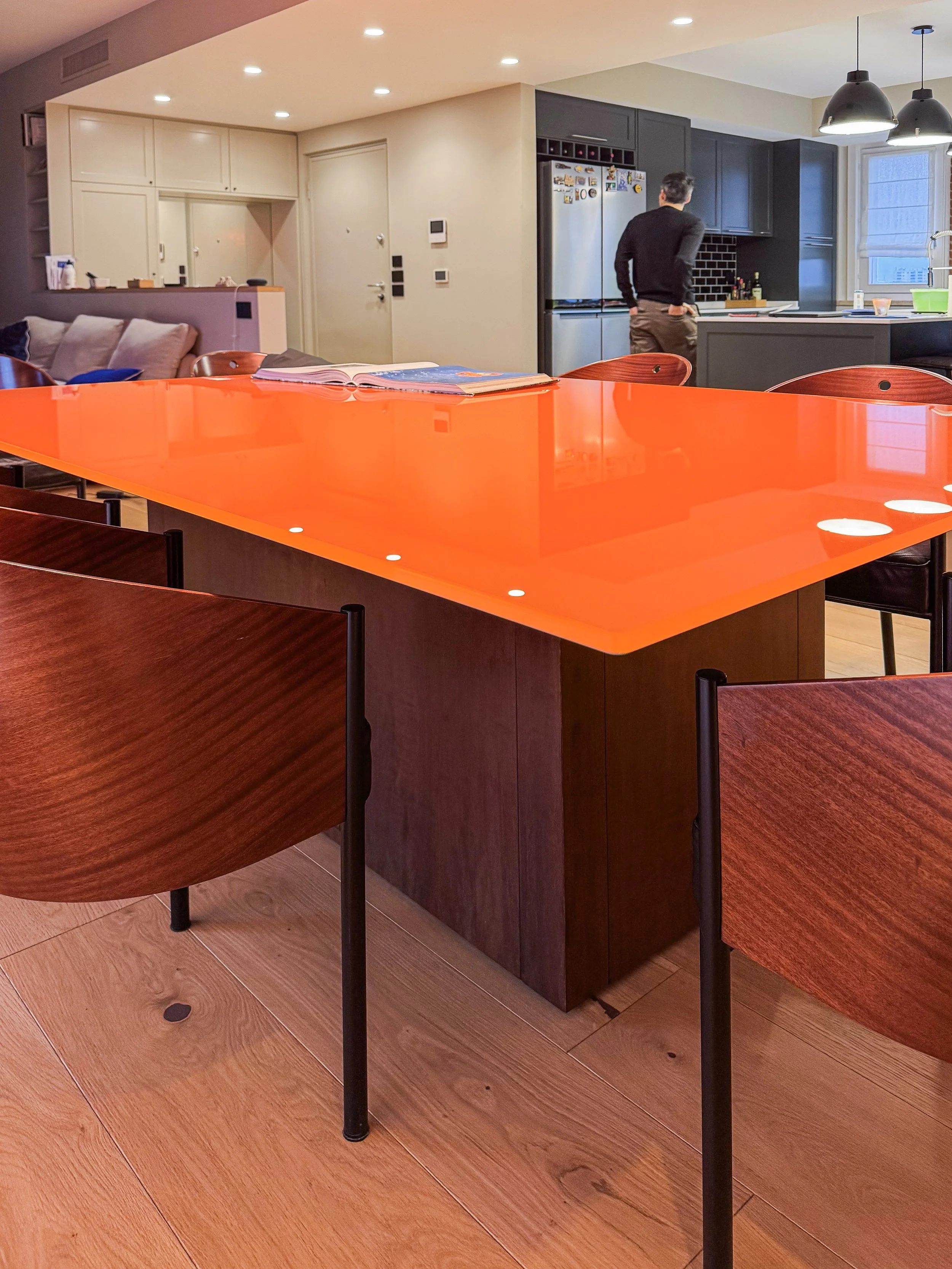Interno di un'appartamento con cucina moderna e tavolo di colore arancione brillante.