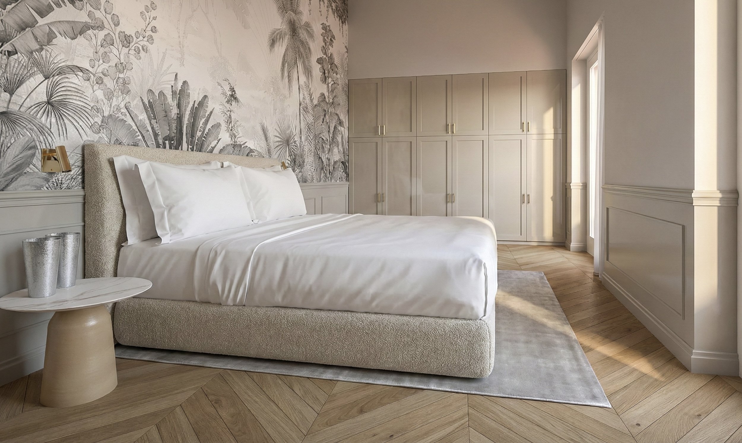 Camera da letto con letto bianco, testata imbottita, pareti con carta da parati a tema tropicale in toni nocciola, armadio grande in legno chiaro, finestra che lascia entrare luce naturale, tappeto grigio chiaro e tavolino rotondo con vasi argentati.