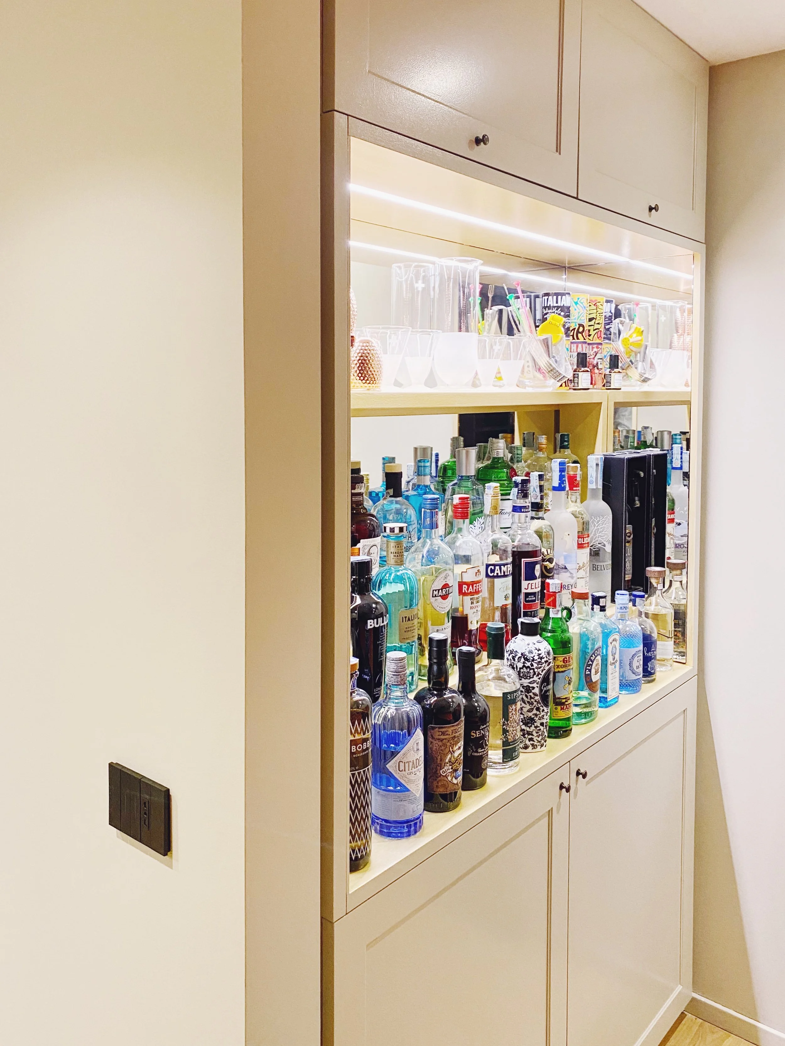 Vetrina con bottiglie di alcolici e bicchieri sullo scaffale.