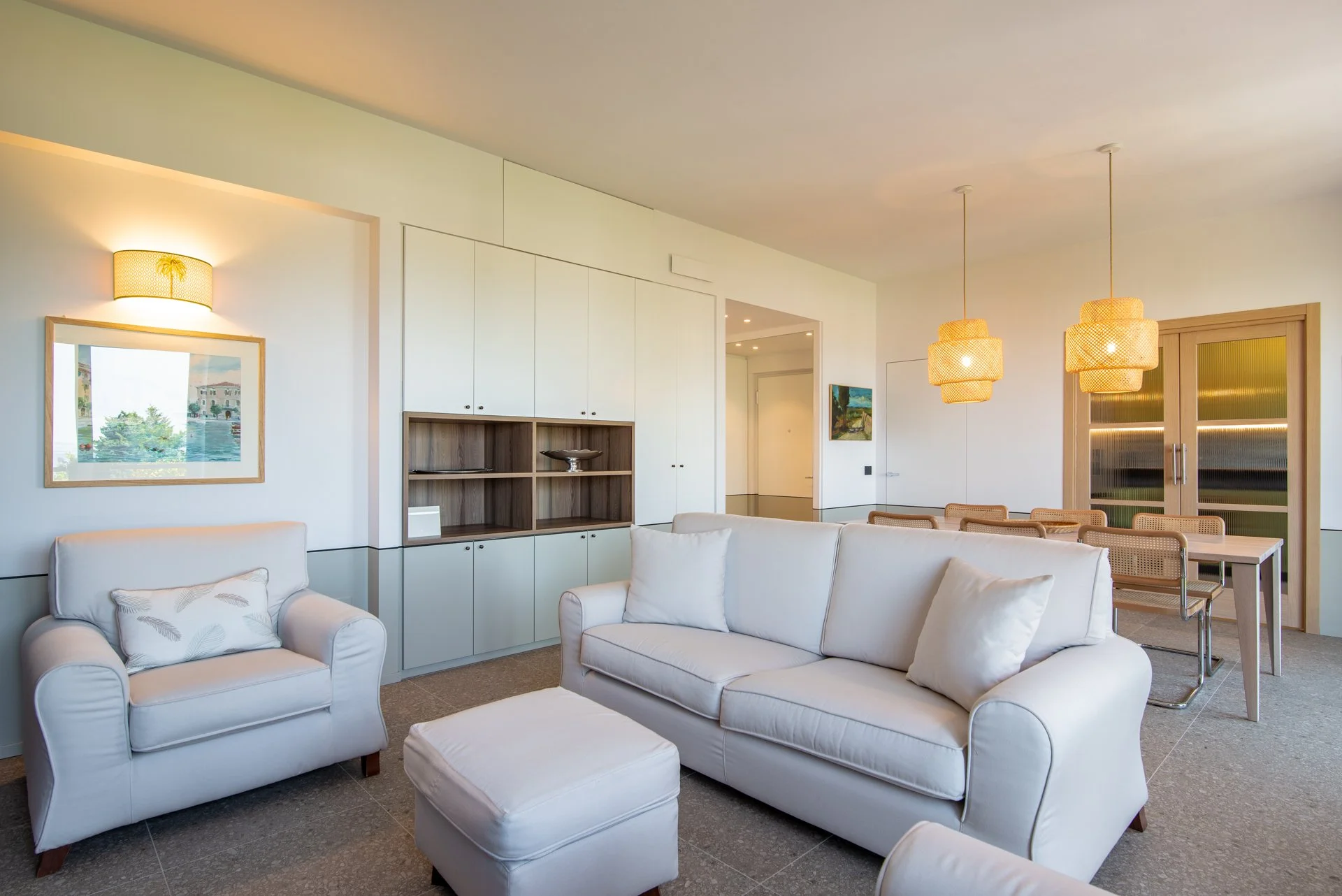 Salotto moderno con divano bianco, poltrona, tavolino, libreria e illuminazione calda