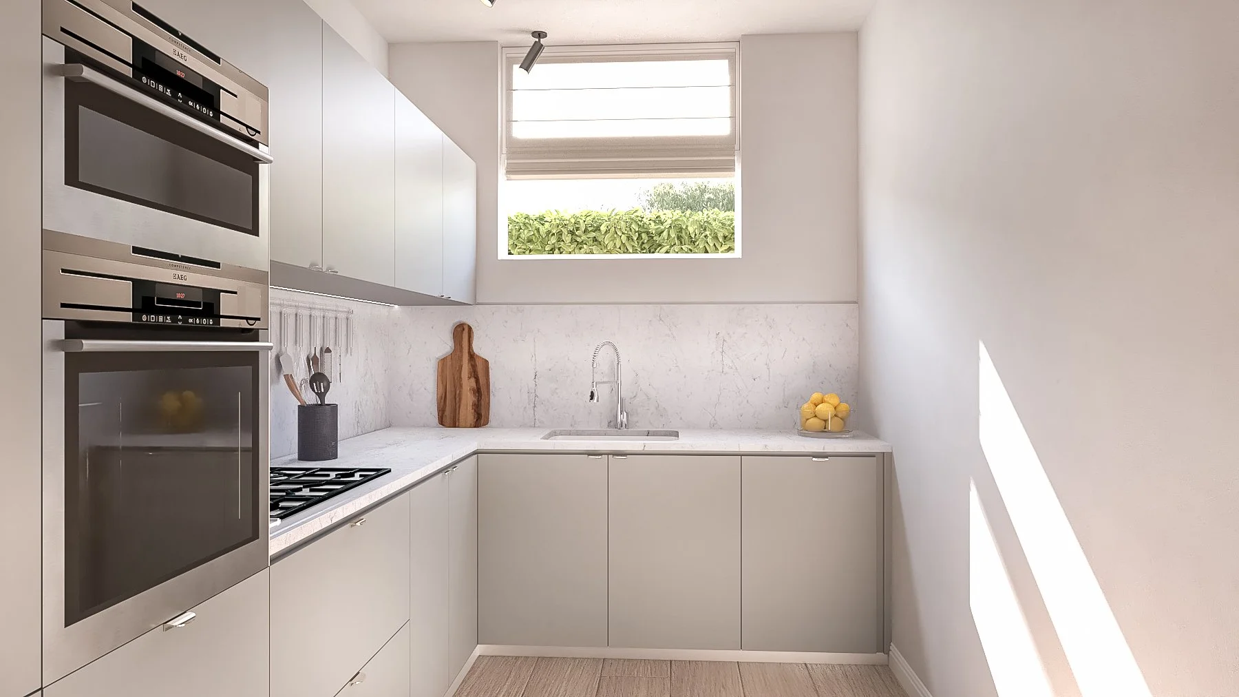 Cucina moderna con pareti bianche, mobili grigi, lavabo sotto finestra, forno e microonde integrati, utensili da cucina e limoni in una ciotola.