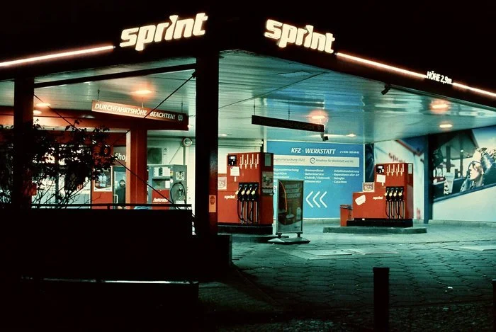 Dettaglio della fotografia artistica 'Gas Station' di Ole Lerche. Una stazione di servizio Sprint fotografata di notte con estetica cinematografica CineStill 800T su carta Hahnemühle Fine Art Pearl.