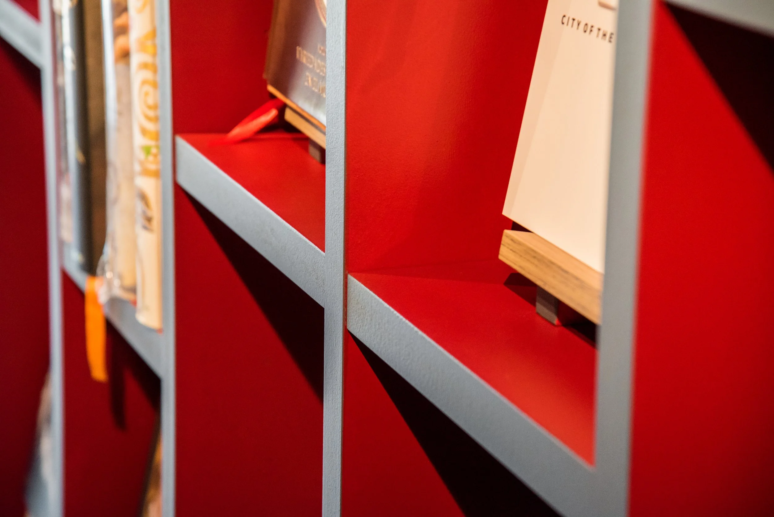 Mensola rossa con libri e oggetti non chiaramente visibili, vista laterale