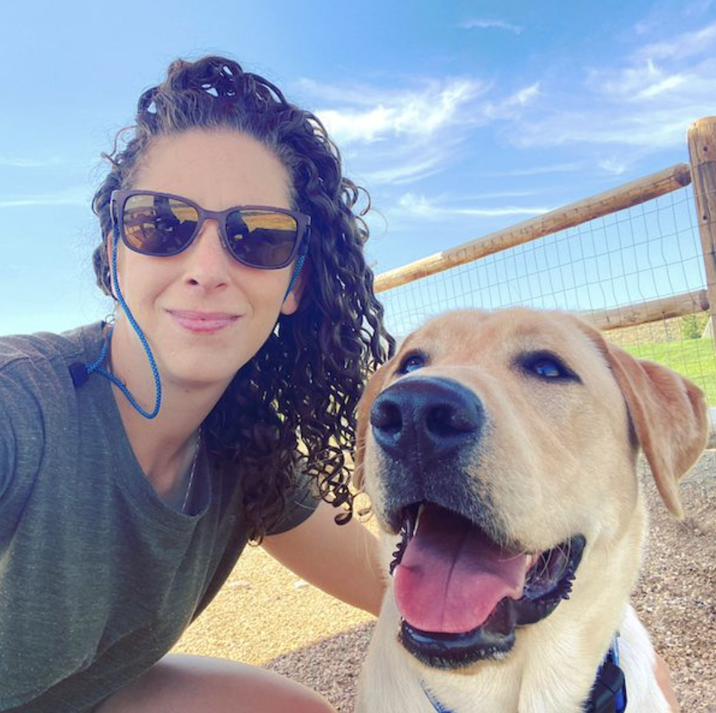 Woman with curly hair and sunglasses with her yellow Labrador Retriever dog