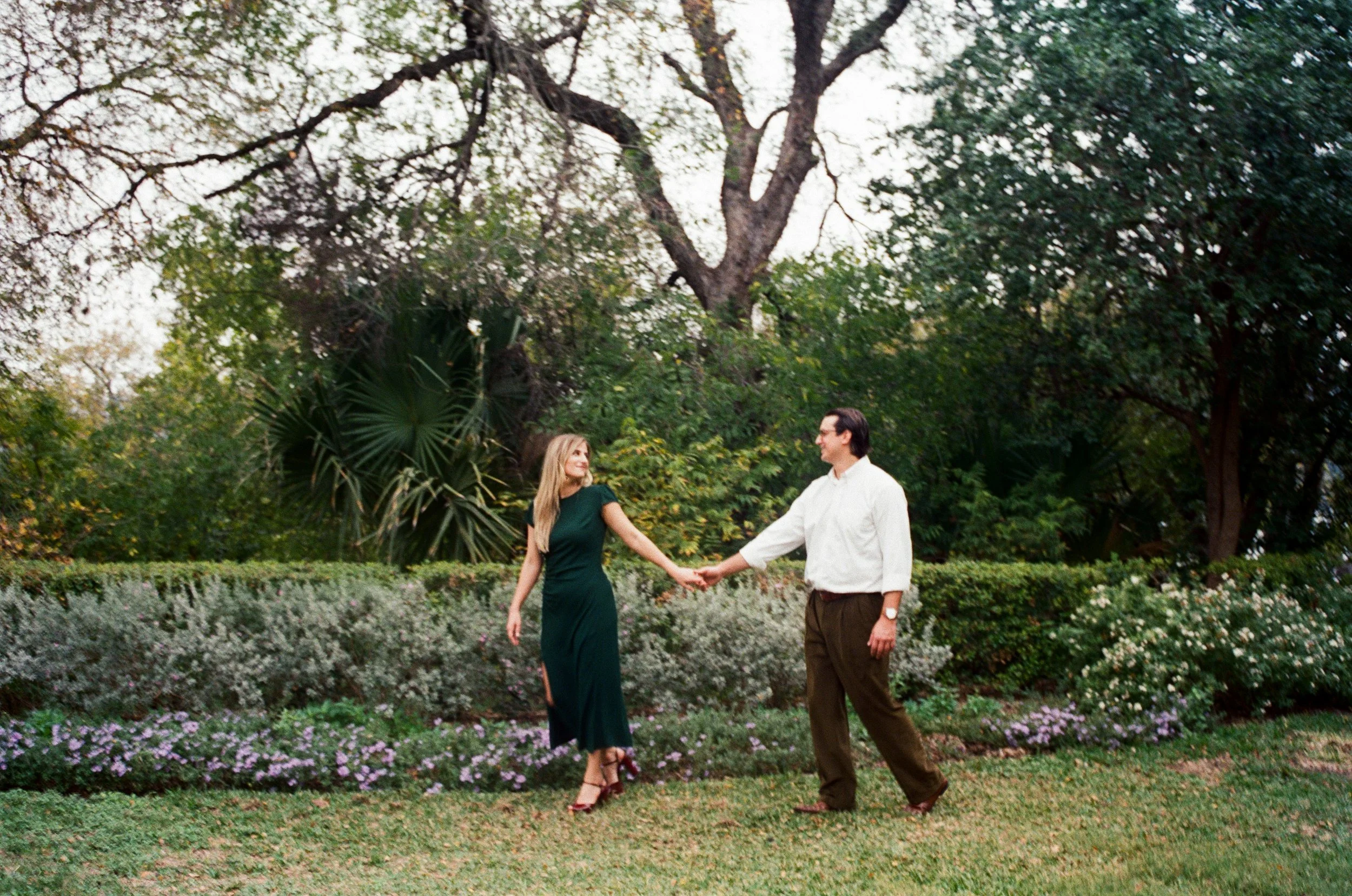 Photo of couple holding hands walking in a garden