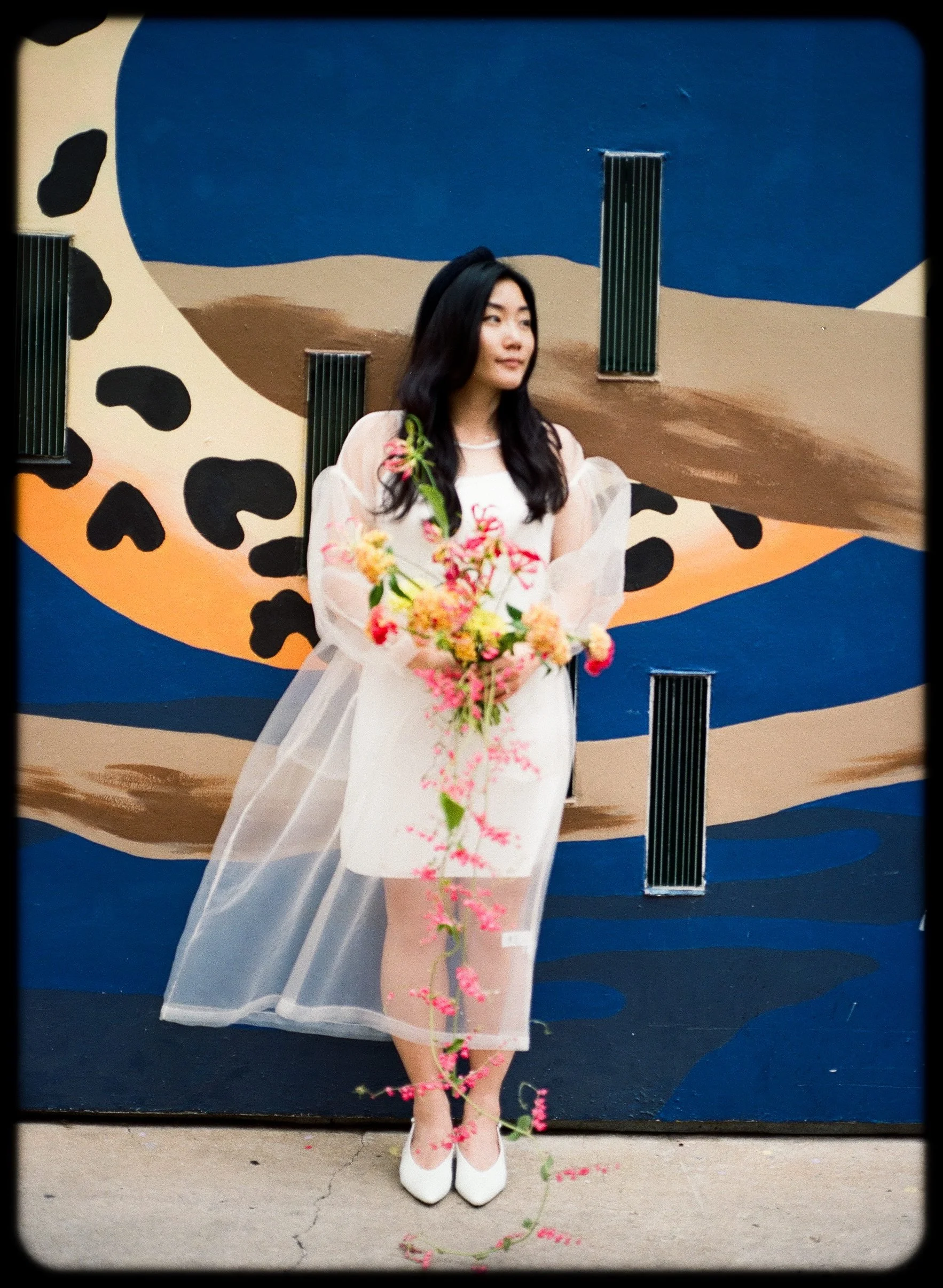 Bride with bouquet in front of graphic mural