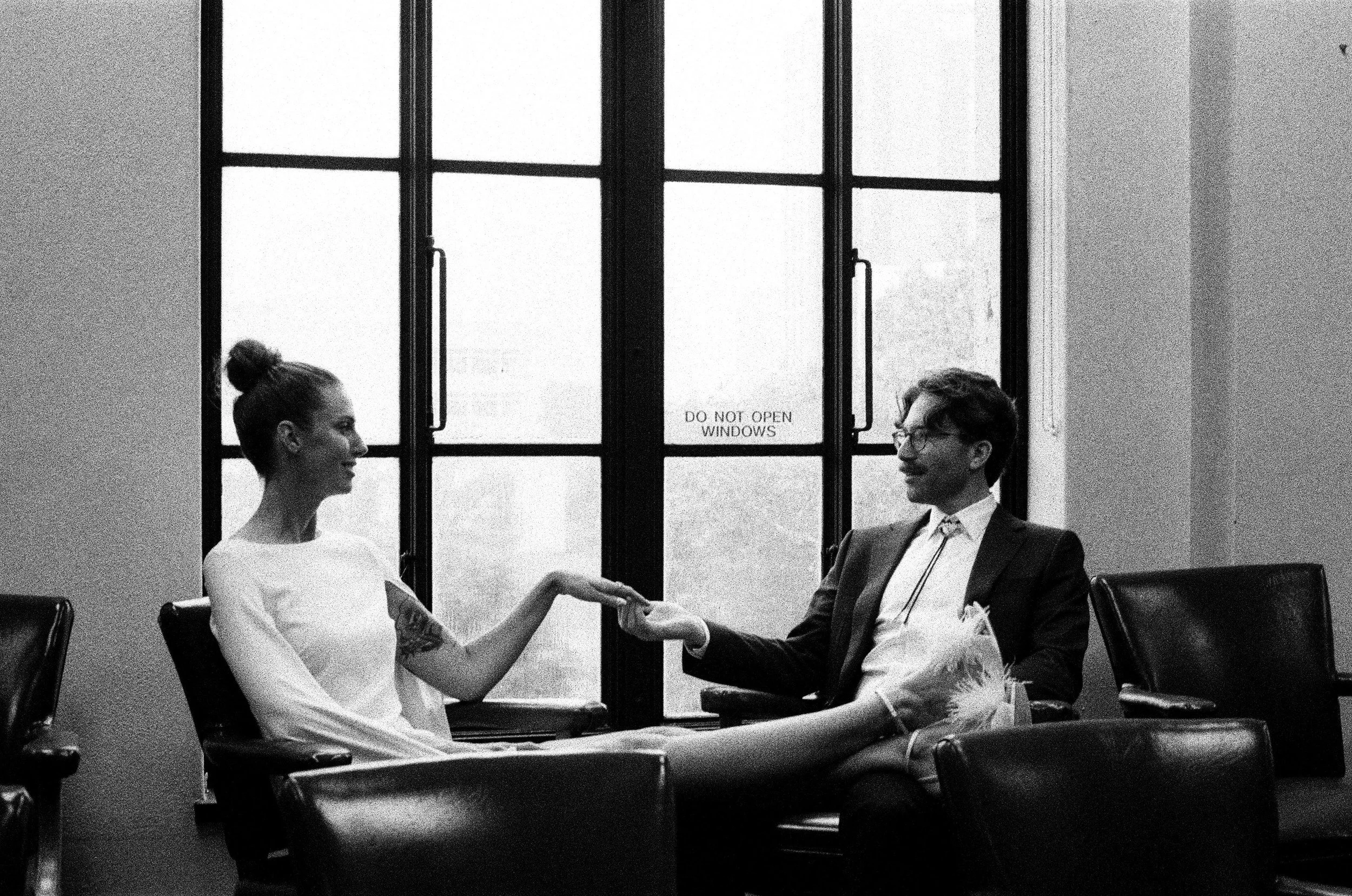 Black and white photo of couple sitting in jury box at courthouse elopement