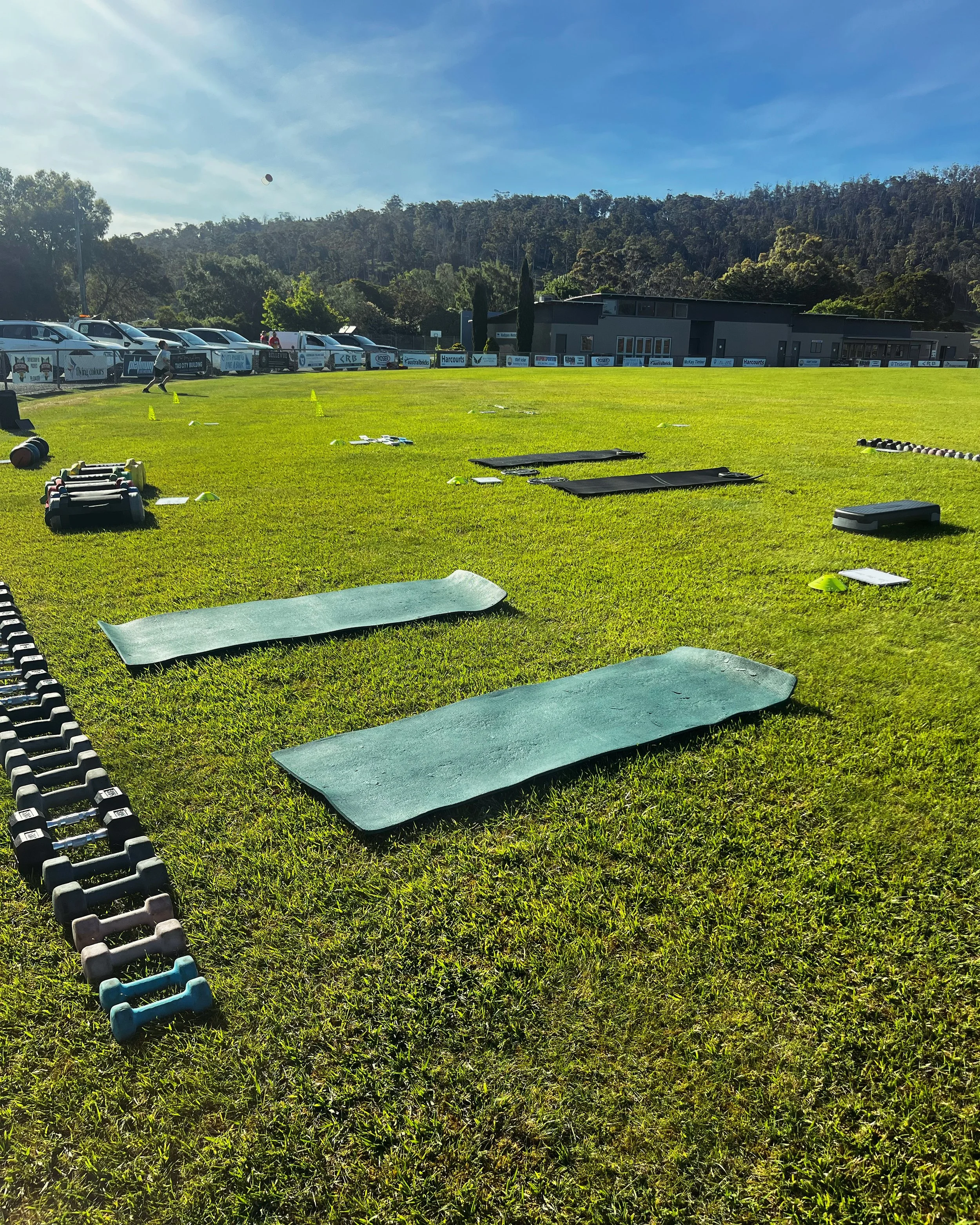 Outdoor fitness area with exercise mats and weights on grass field