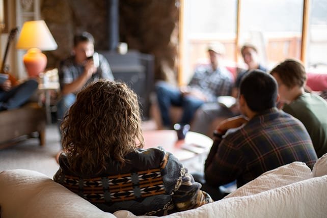Grupo de personas en una reunión en un salón acogedor con luz natural y decoraciones cálidas. Leyendo la Biblia y compartiendo el mensaje de Jesús