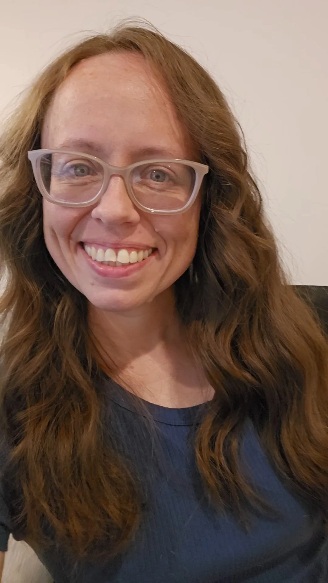 Katie Van Hughes, owner of GSD Bookkeeping Services LLC, sits smiling at the camera. She has long, wavy brown hair and glasses.