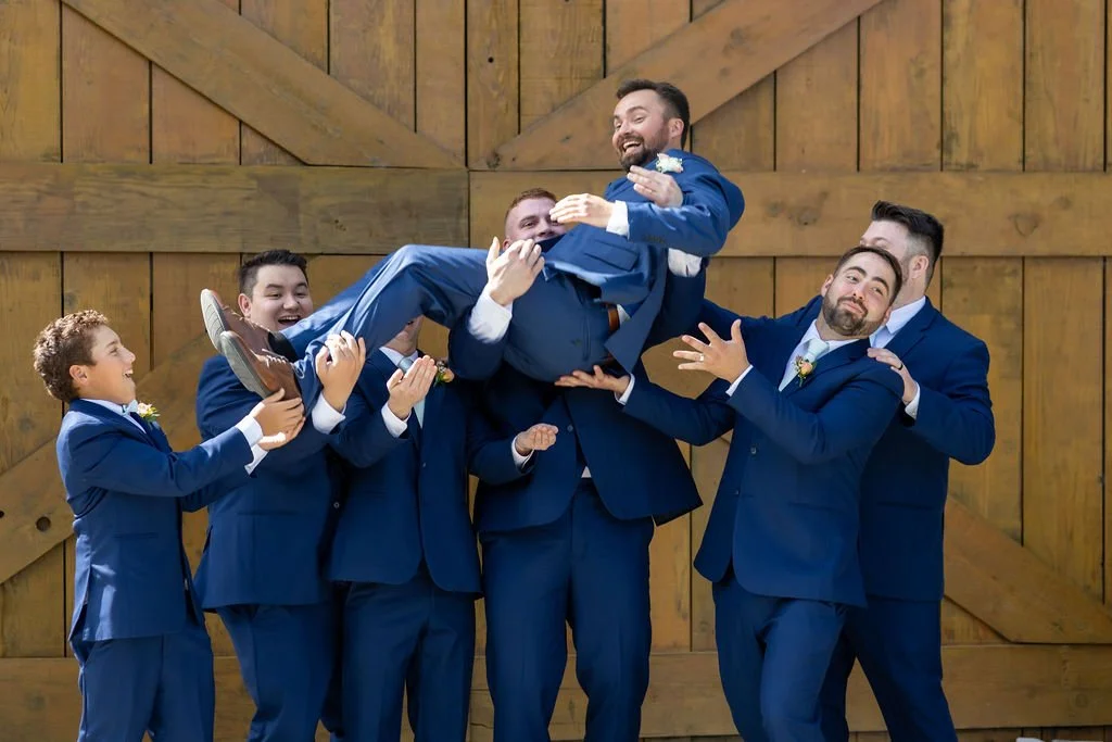 Groomsmen lifting the groom outside the barn at Tar Creek Ranch