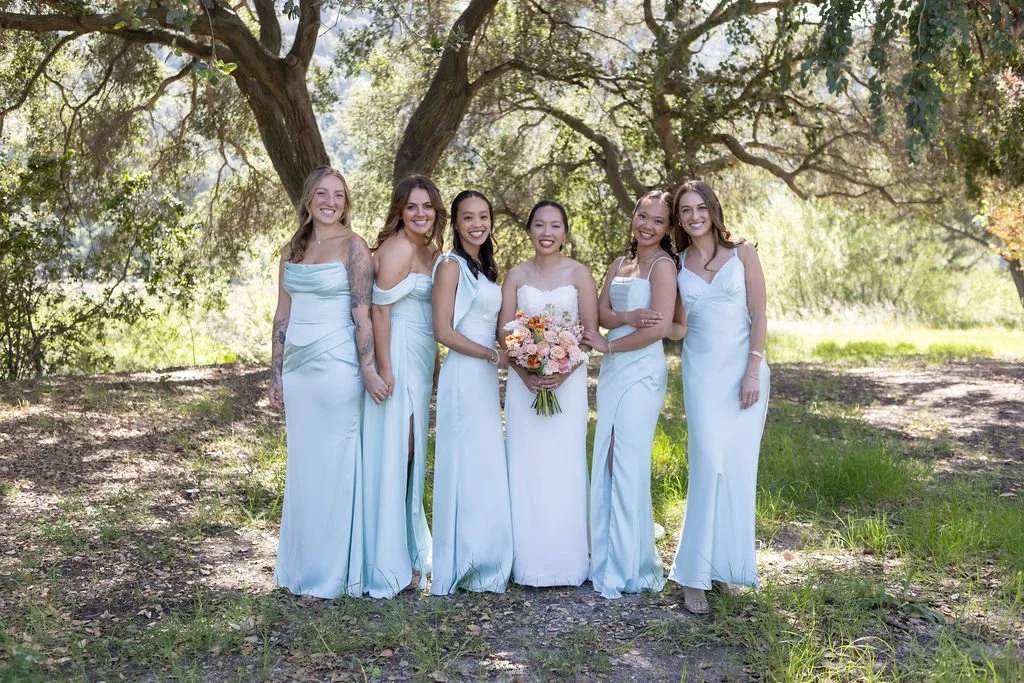 Ariana with bridesmaids in icy blue dresses beneath oak trees at Tar Creek Ranch
