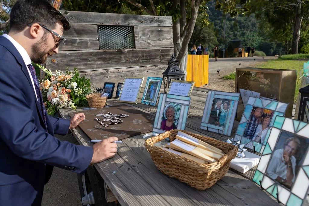 Wedding guest signing a keepsake board at a Central Coast ranch reception