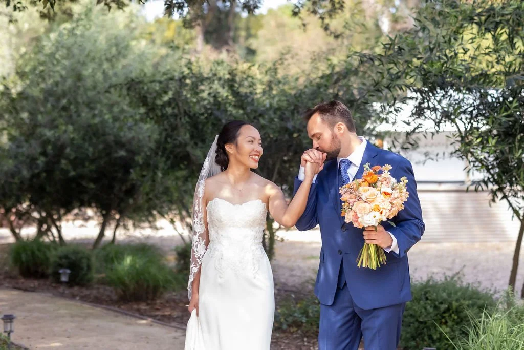 Groom kissing the bride’s hand during a spring wedding at Tar Creek Ranch