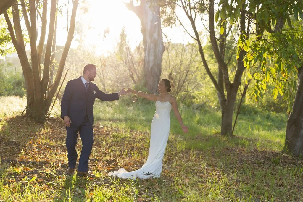 Newlyweds twirling beneath the trees during golden hour at Tar Creek Ranch